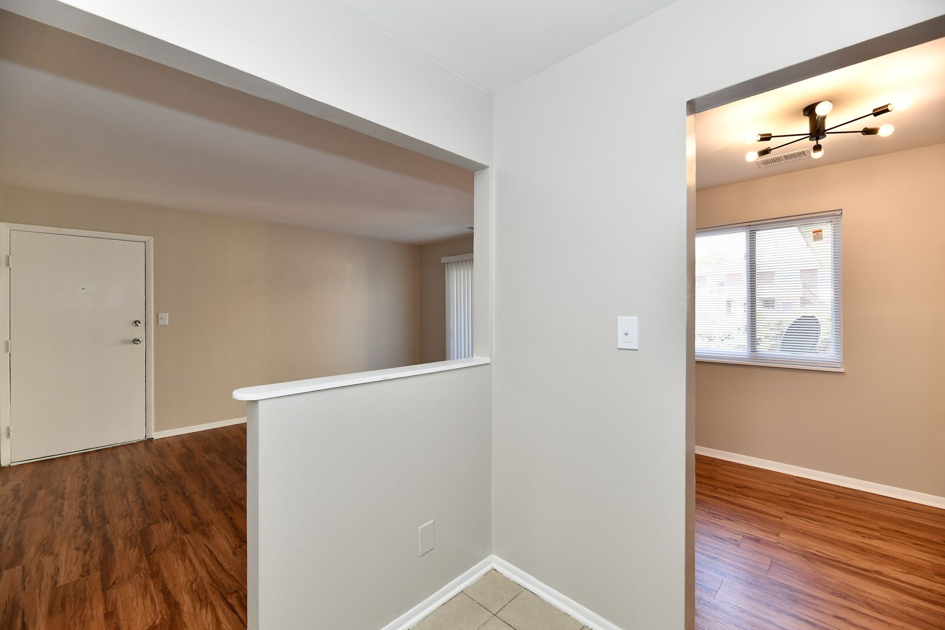 Interior view of an apartment entryway with hardwood floors and open doorways to other rooms.