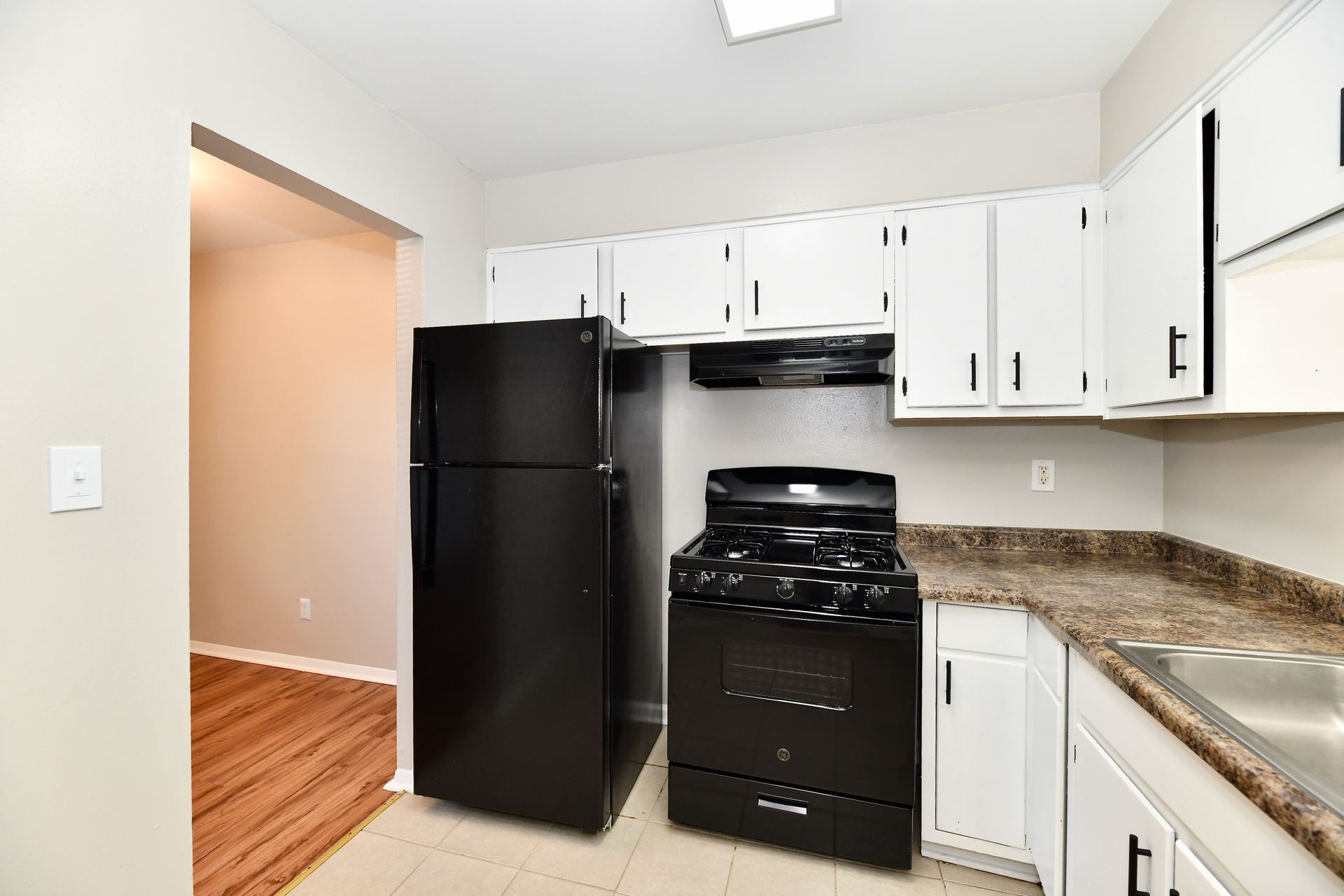 Black appliances in a white kitchen. Includes refrigerator, stove, cabinets, and a countertop.
