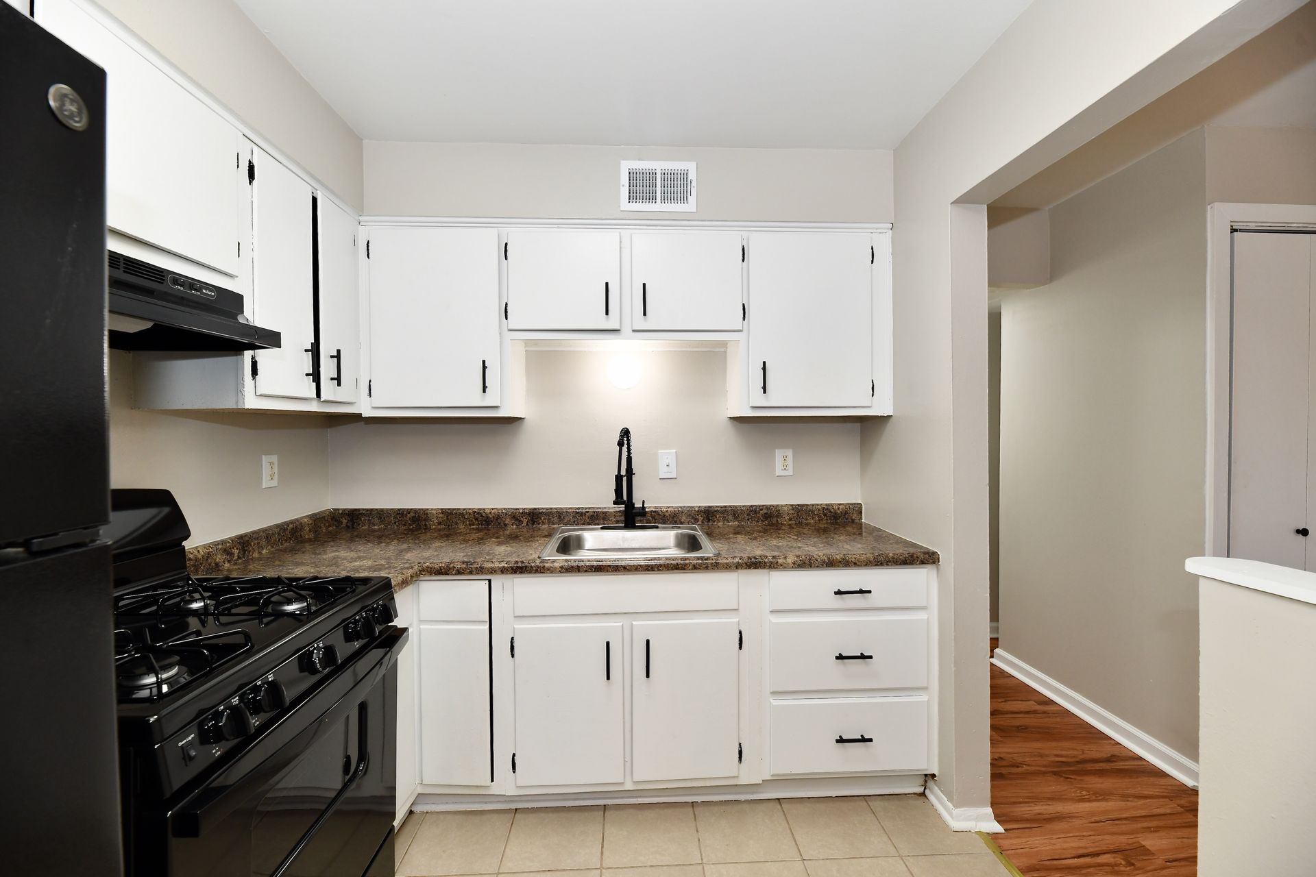 A small, white kitchen with black appliances and a dark countertop.