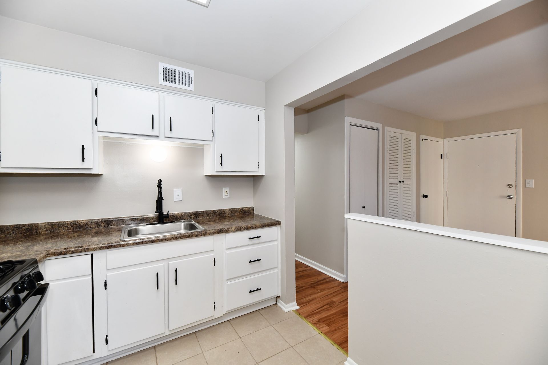 Kitchen with white cabinets, black faucet, and brown countertops.