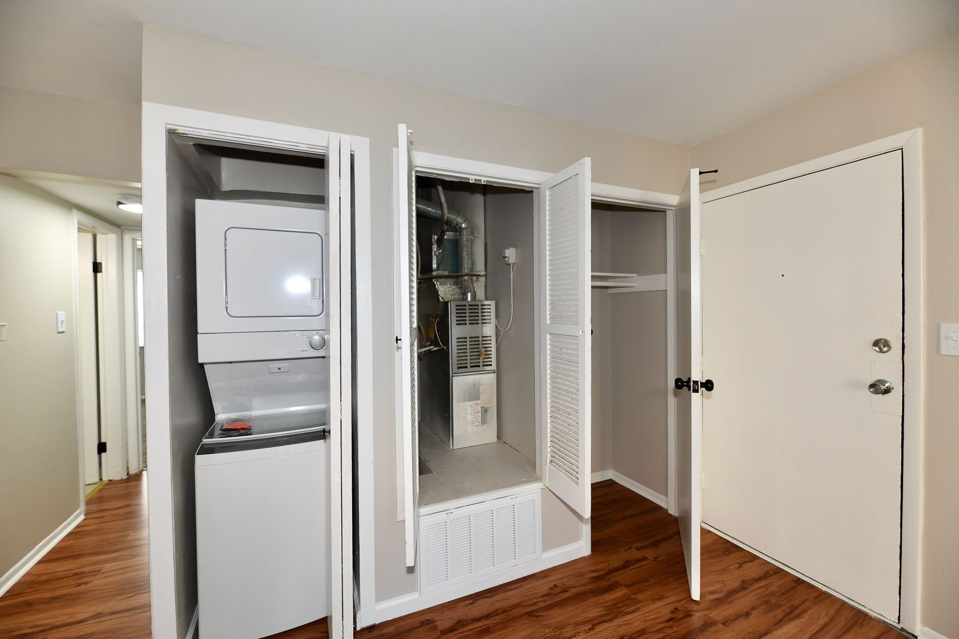 Laundry closet with stacked washer/dryer, furnace, and storage in an apartment.