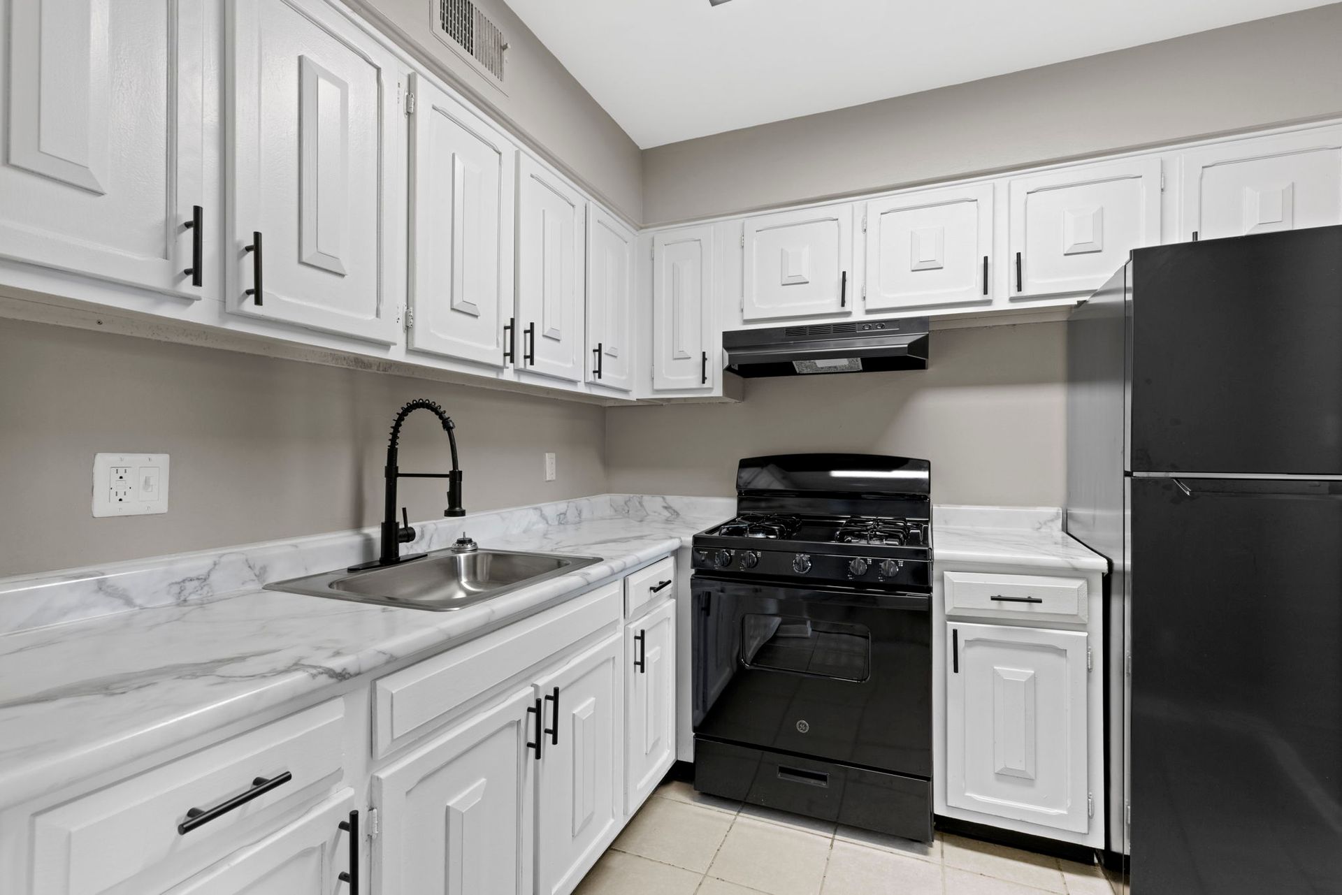 White kitchen with black appliances, cabinets, and fixtures.