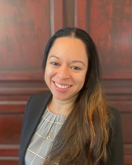 A woman is smiling for the camera in front of a wooden wall.