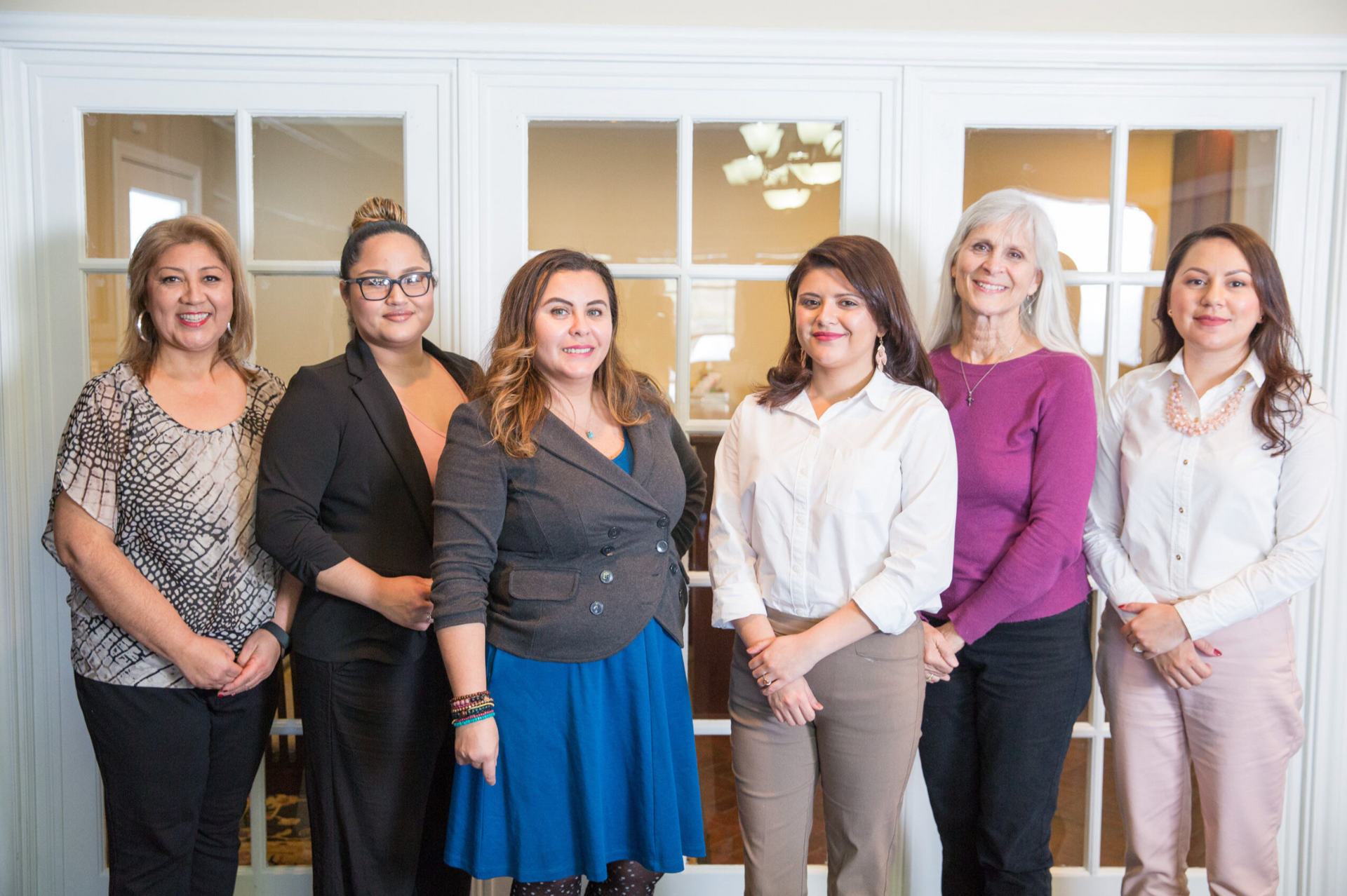 A group of women are posing for a picture in front of a glass door.