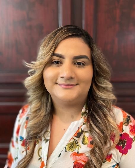 The woman is wearing a floral shirt and smiling for the camera.