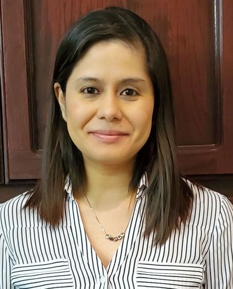 A woman wearing a striped shirt and a necklace is smiling for the camera.