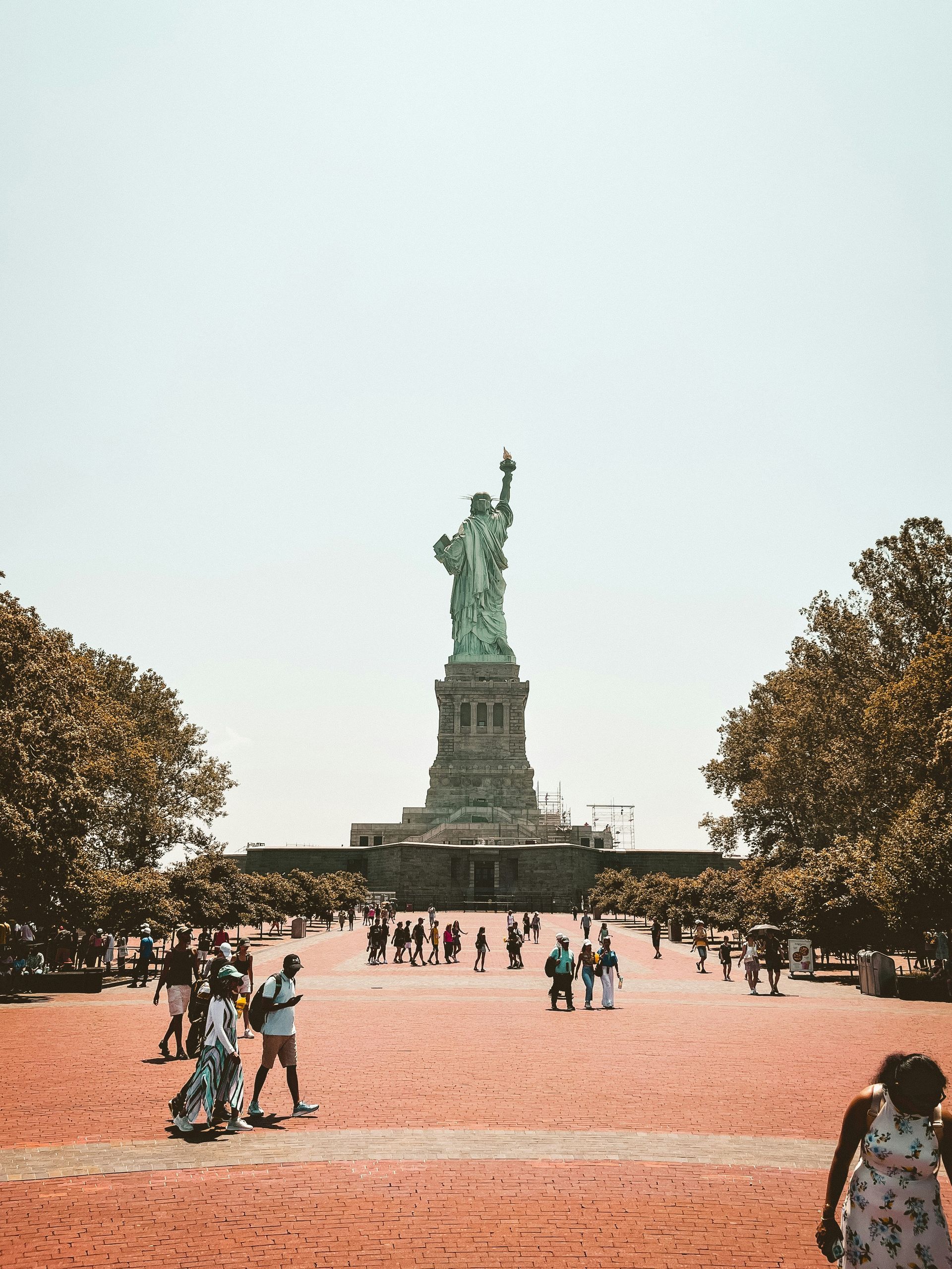 A group of people are standing in front of the statue of liberty.