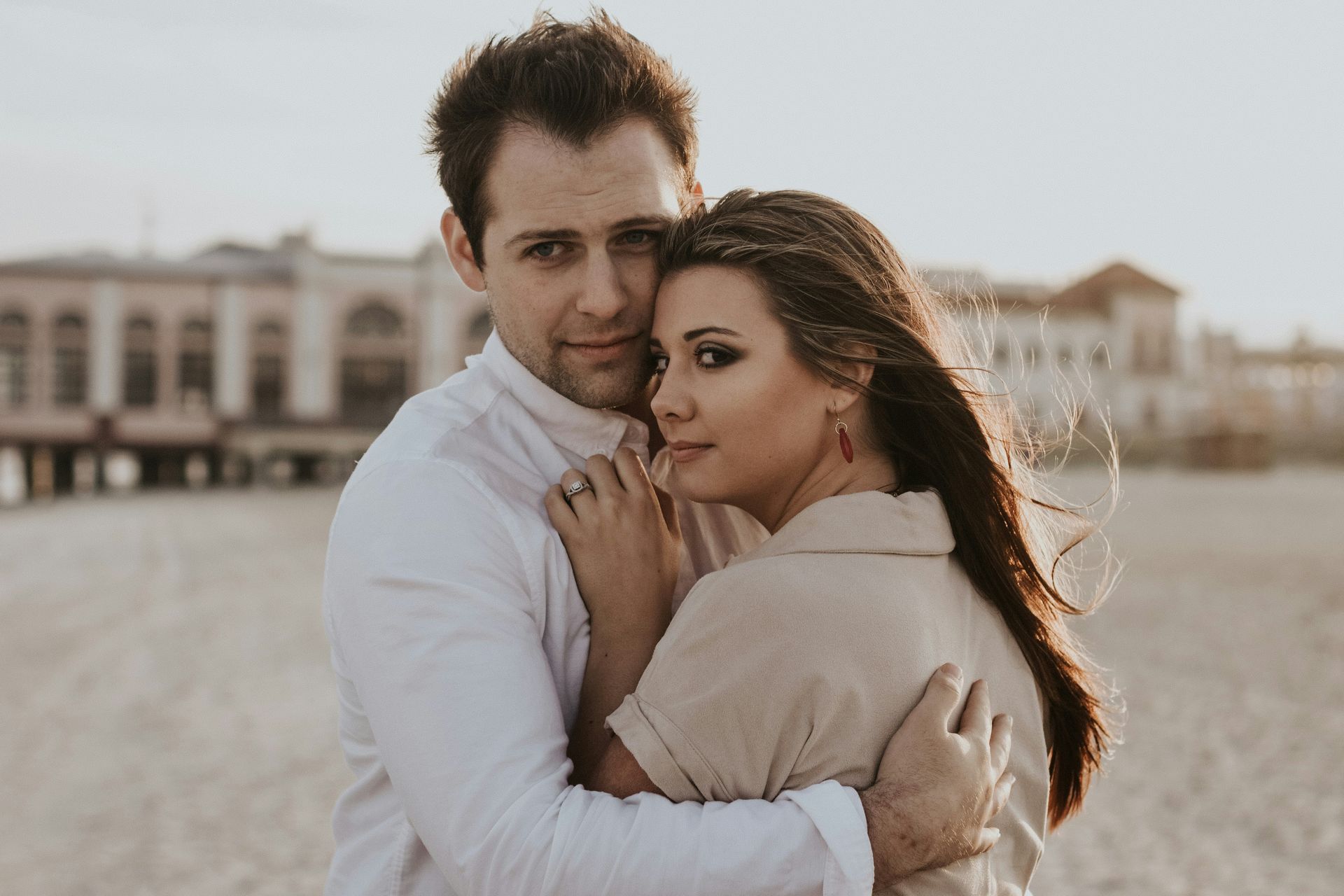 A man and a woman are hugging each other on the beach.