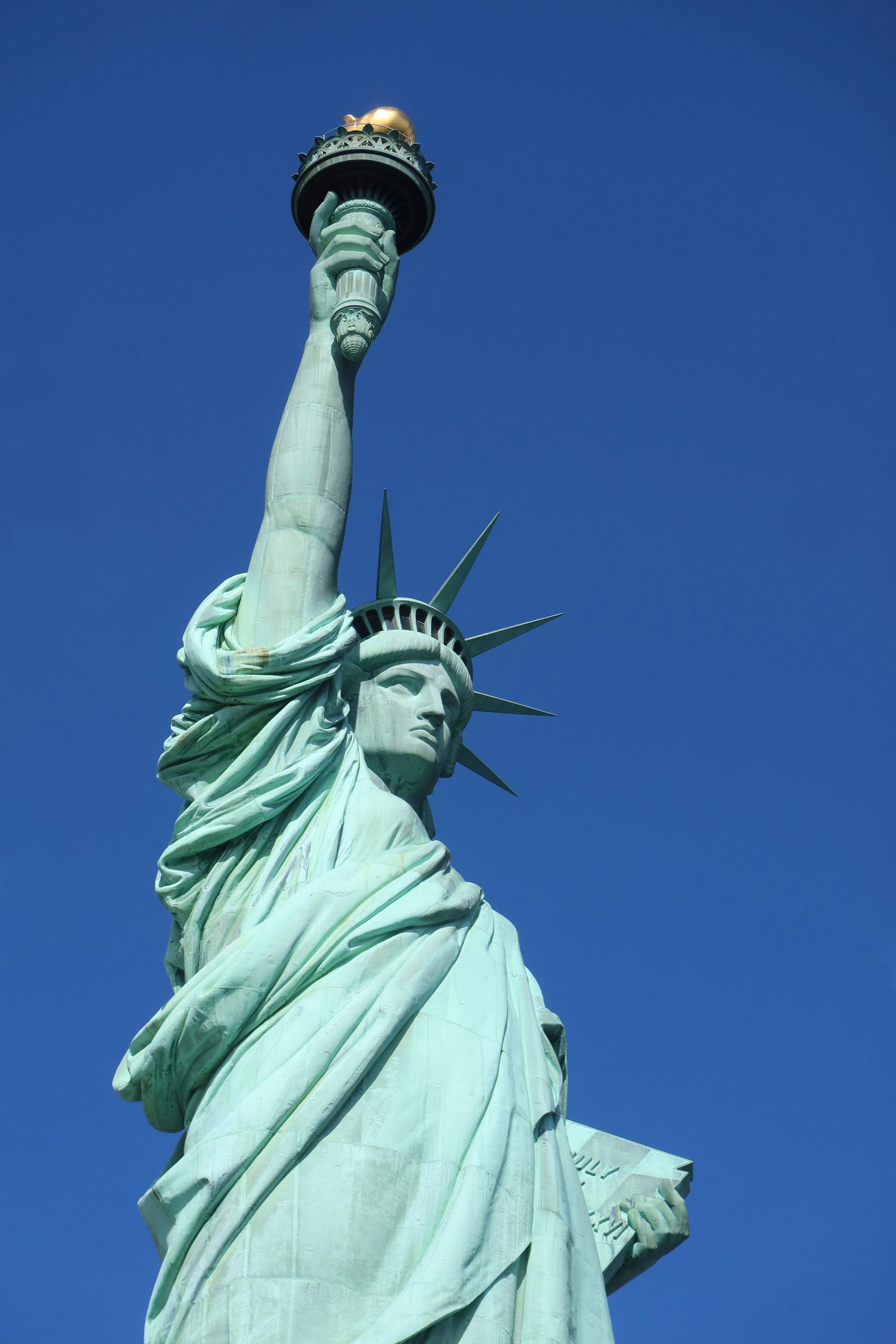 The statue of liberty is against a blue sky