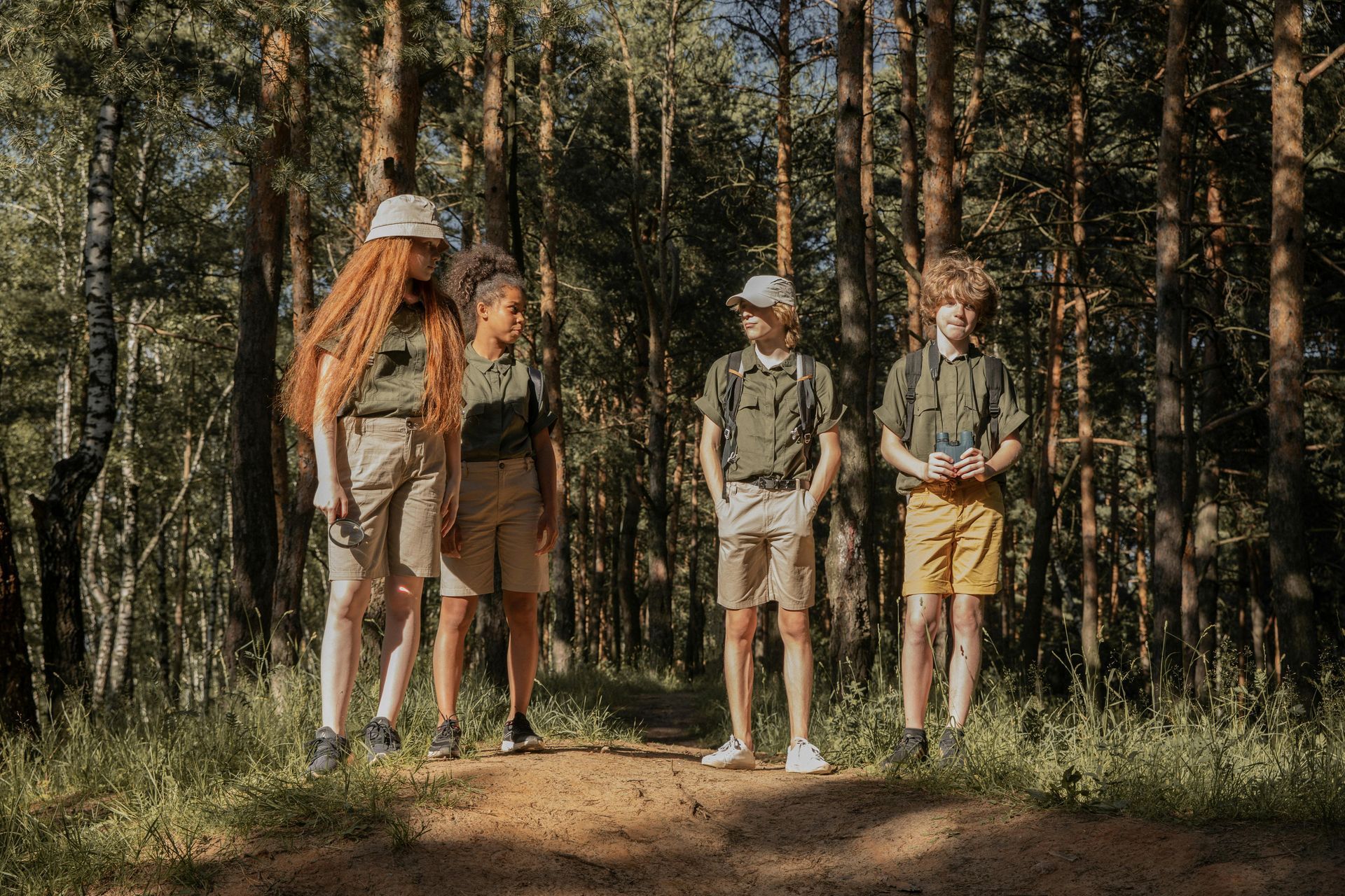 A group of children are standing on a dirt path in the woods.