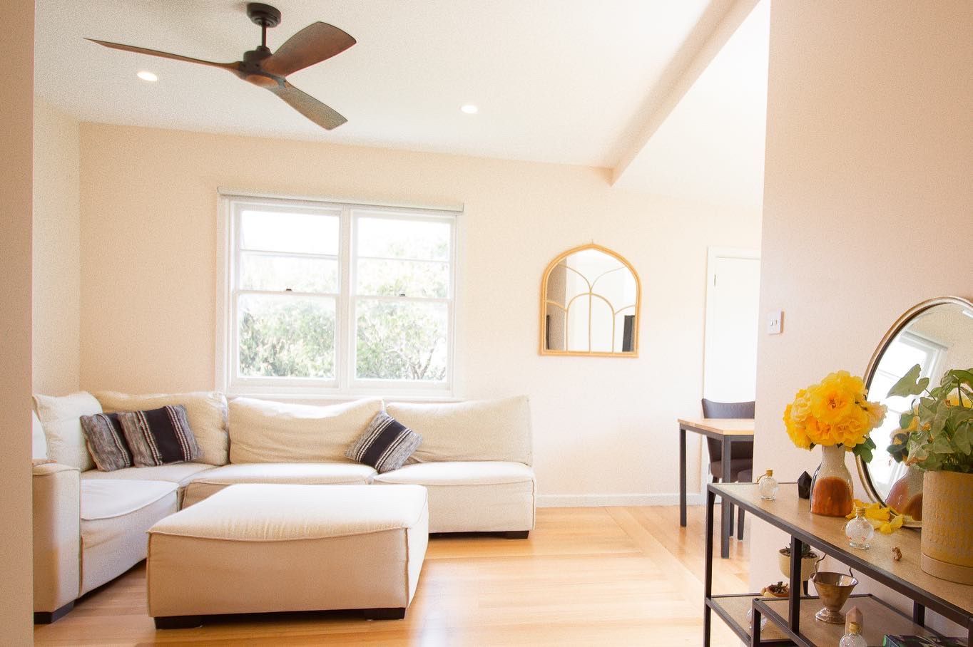 Modern bathroom with a glass-enclosed shower, dark tile walls, and a light wood vanity topped with a green potted plant.