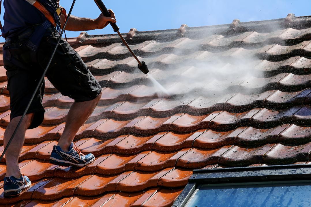 Man is Cleaning a Tiled Roof With a High Pressure Washer — Above All Roof Painters & Repairs in Bribie Island, QLD