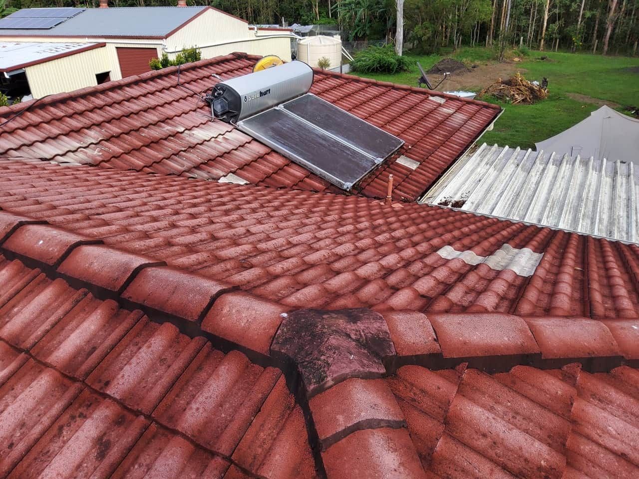 A red tiled roof with a solar panel on top of it. — Above All Roof Painters & Repairs in Bellmere, QLD