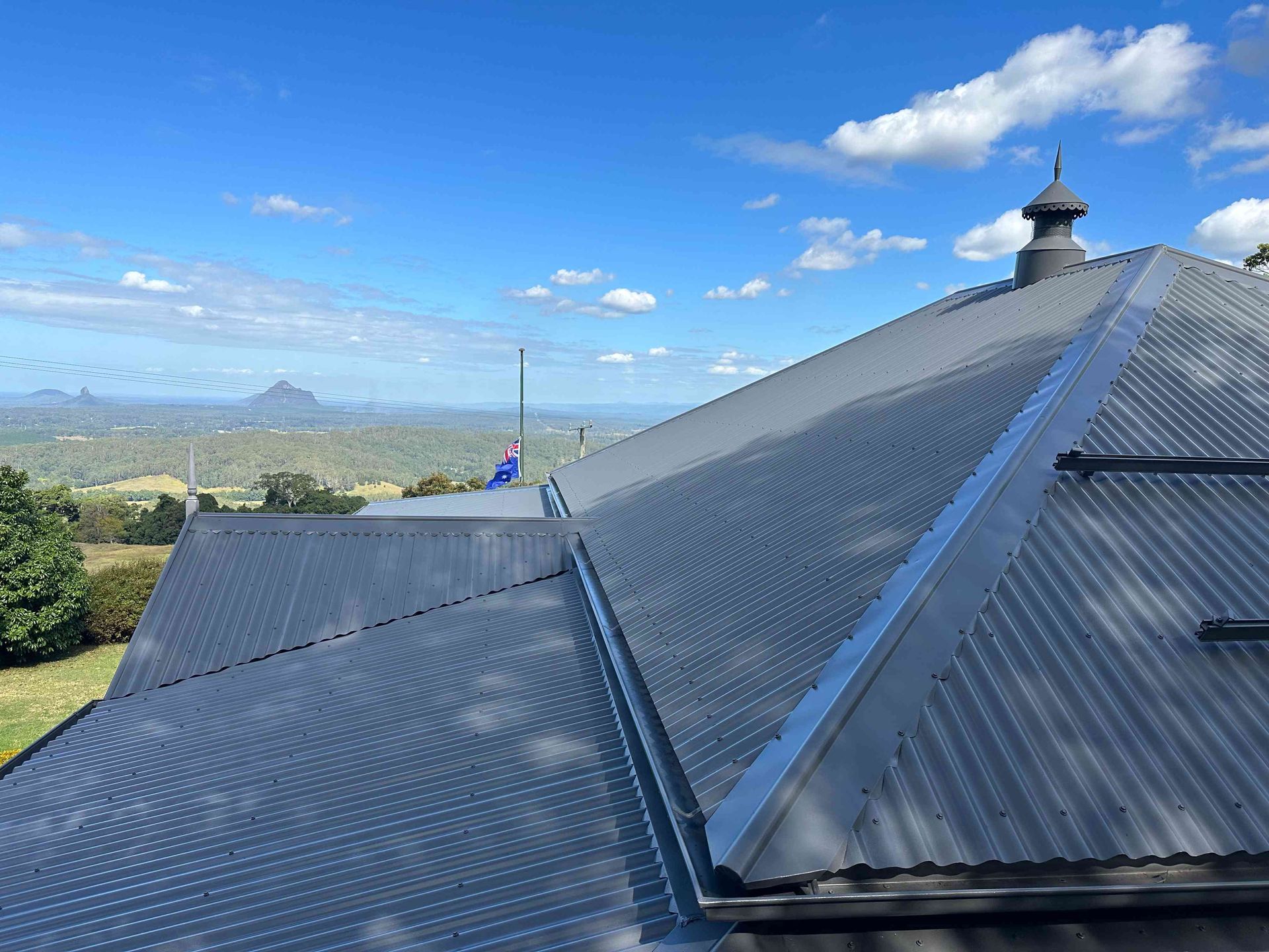 The roof of a house with a view of a valley and mountains. — Above All Roof Painters & Repairs in Bellmere, QLD