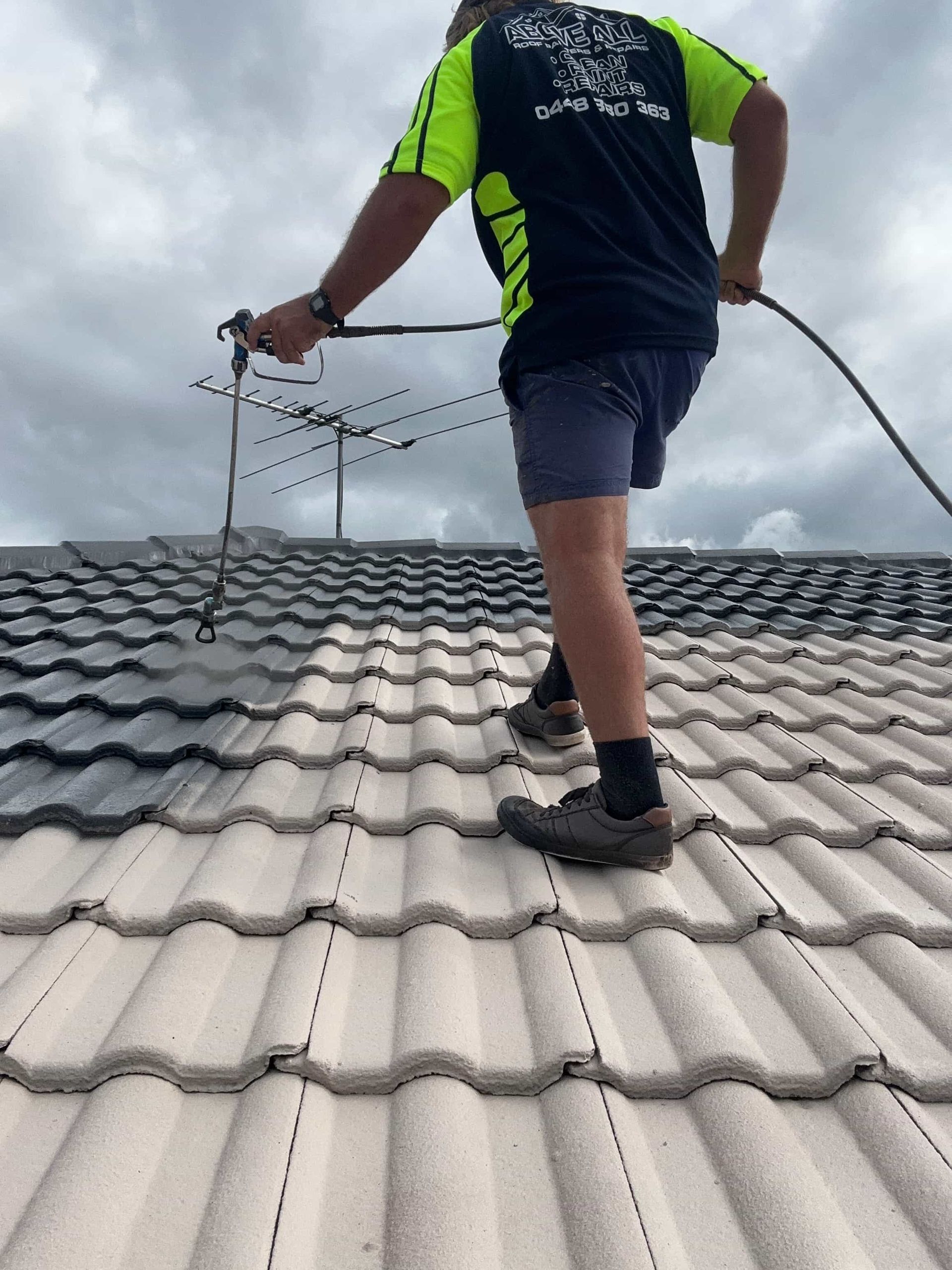 A man is spraying a roof with a hose. — Above All Roof Painters & Repairs in Bribie Island, QLD