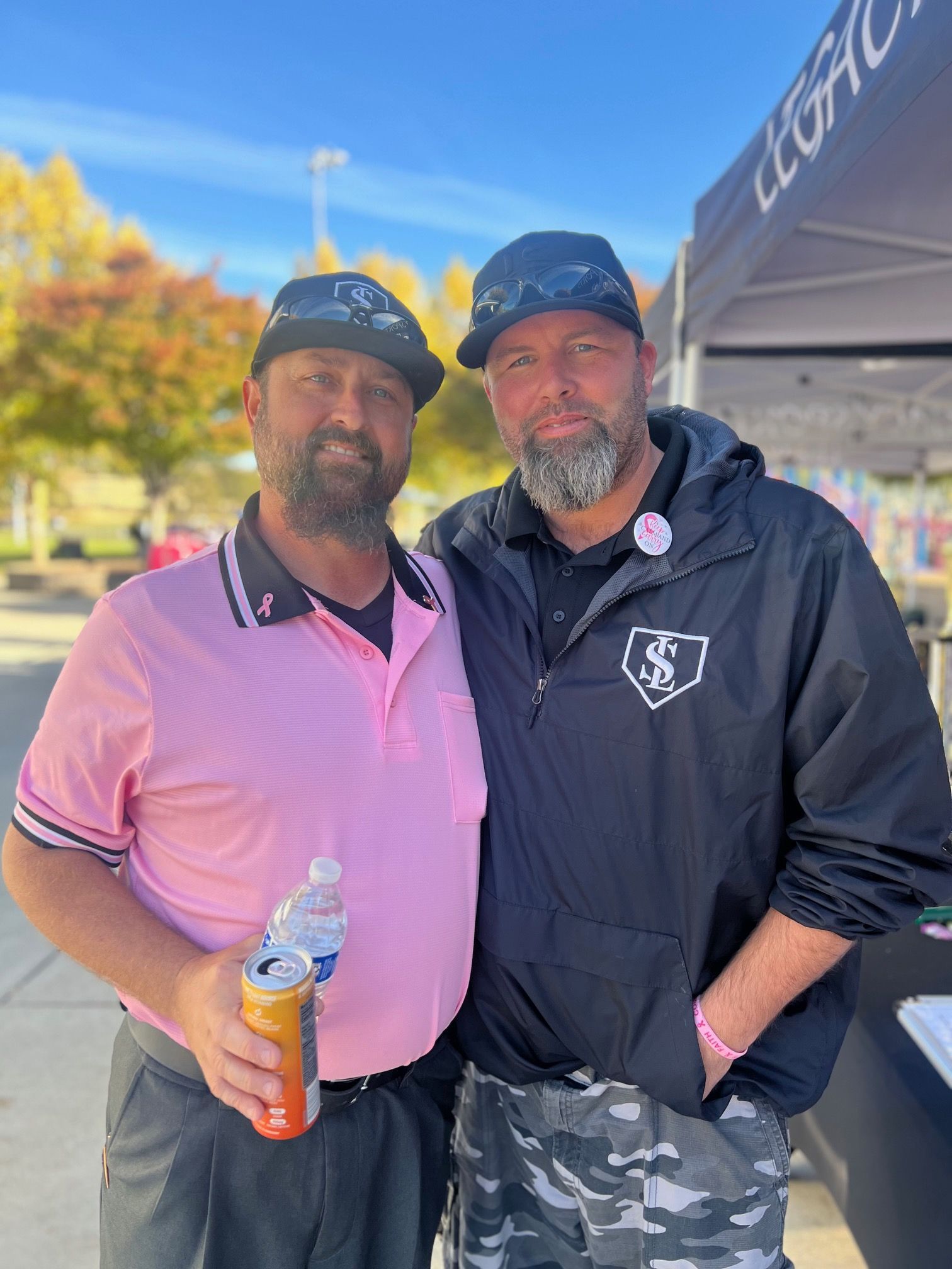 Two men are standing next to each other in front of a tent.