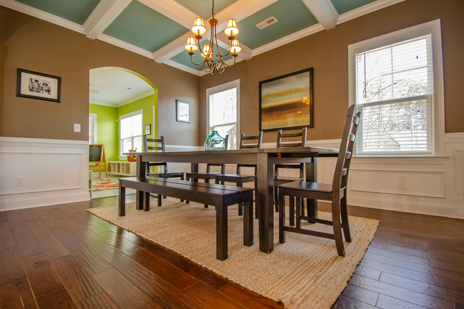 Dining room with dark wood table, teal ceiling, chandelier, and hardwood floors