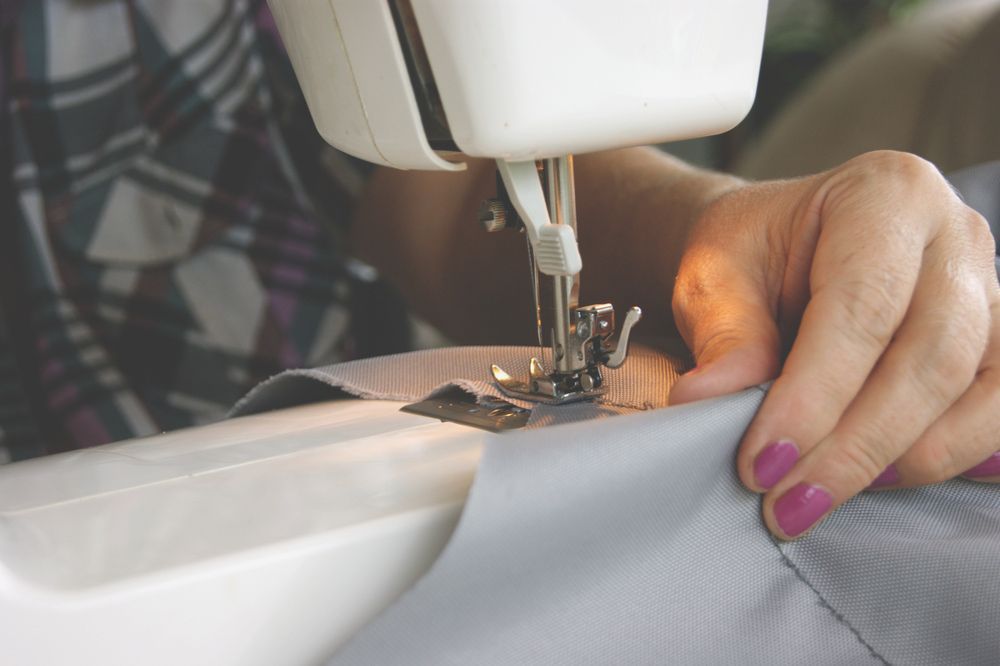 A Woman Is Using A Sewing Machine To Sew A Piece Of Fabric — The Sewing Machine Doctor In Forest Glen, QLD