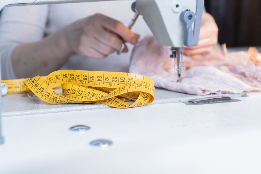 A Person Is Using A Sewing Machine With A Measuring Tape On The Table — The Sewing Machine Doctor In Forest Glen, QLD