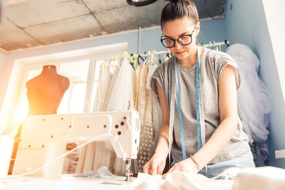 A Woman Is Using A Sewing Machine In A Workshop — The Sewing Machine Doctor In Forest Glen, QLD