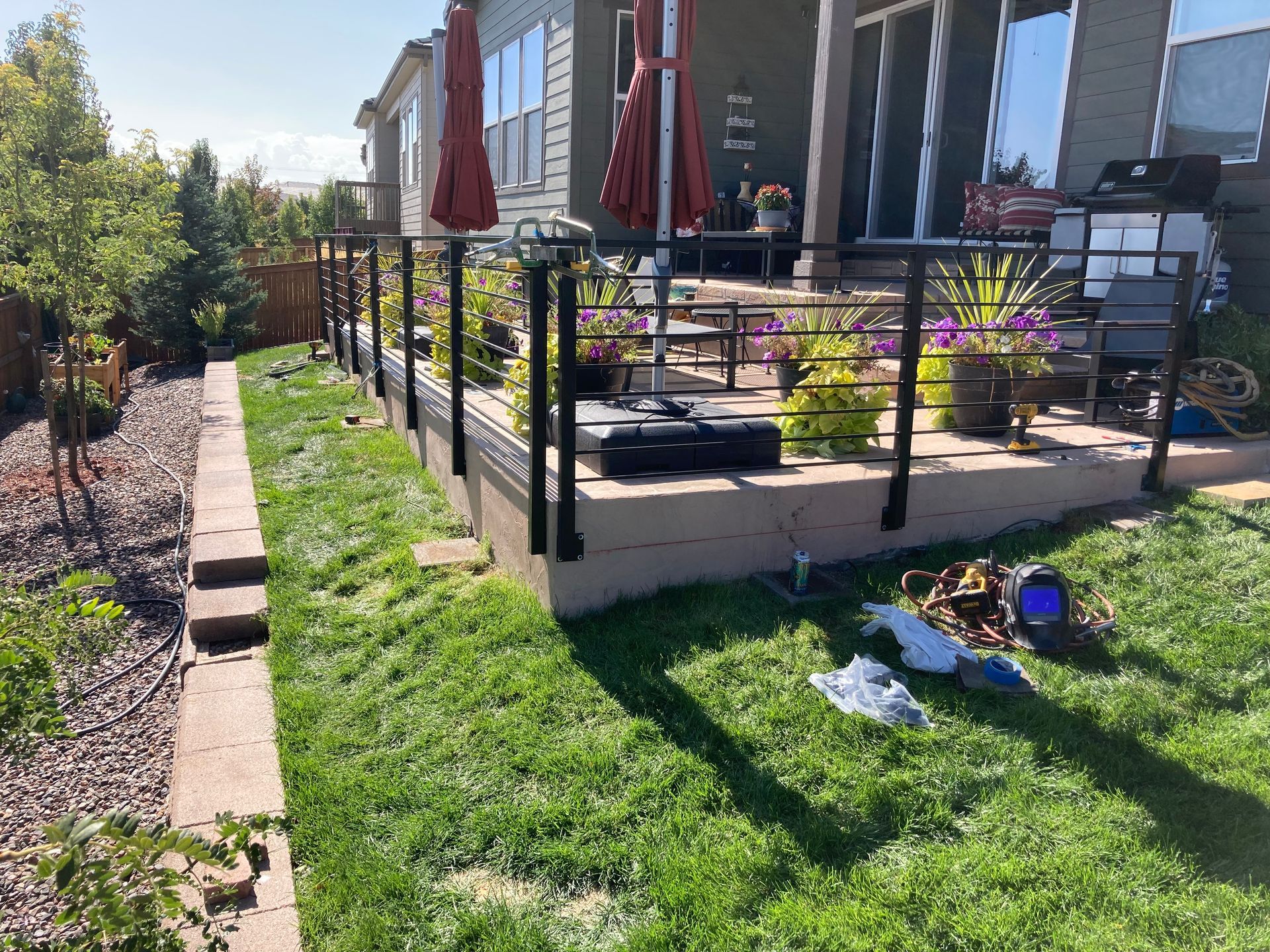 Backyard with a deck, black railing, and green lawn; sunny day.