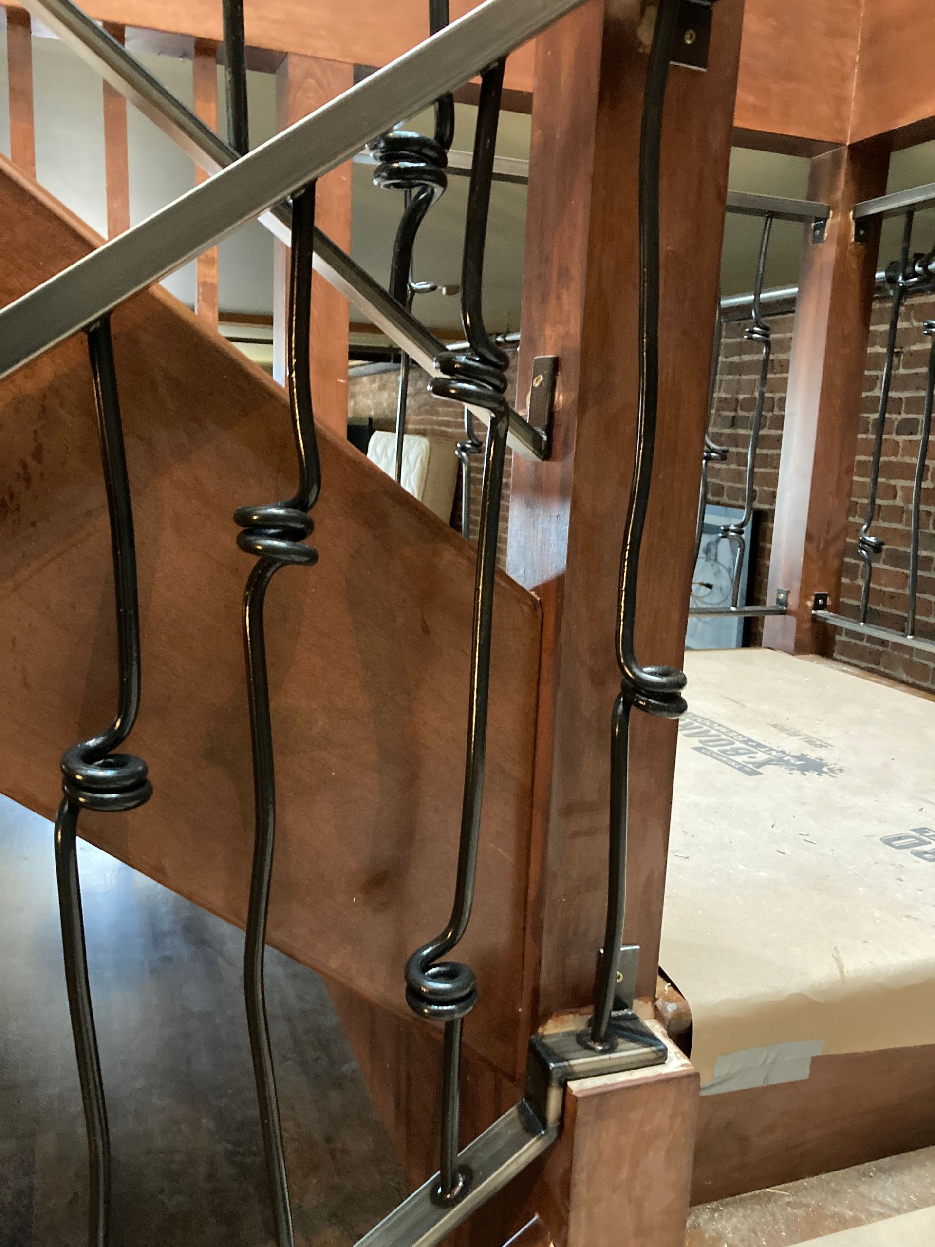 Black metal stair railing with spiral details on a wooden staircase.