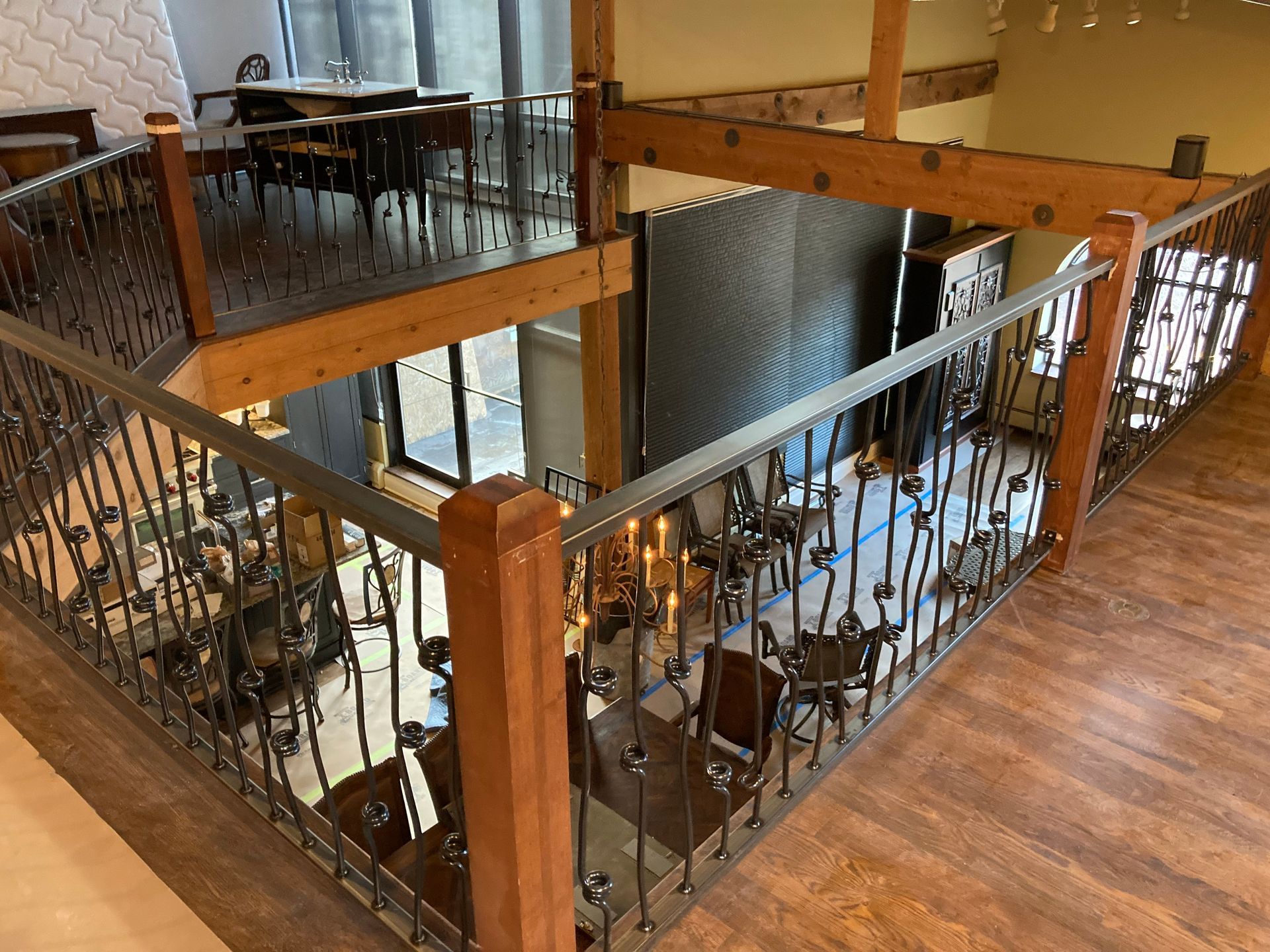 Interior view of a restaurant with a second-floor balcony, wood floors, and decorative wrought iron railings.