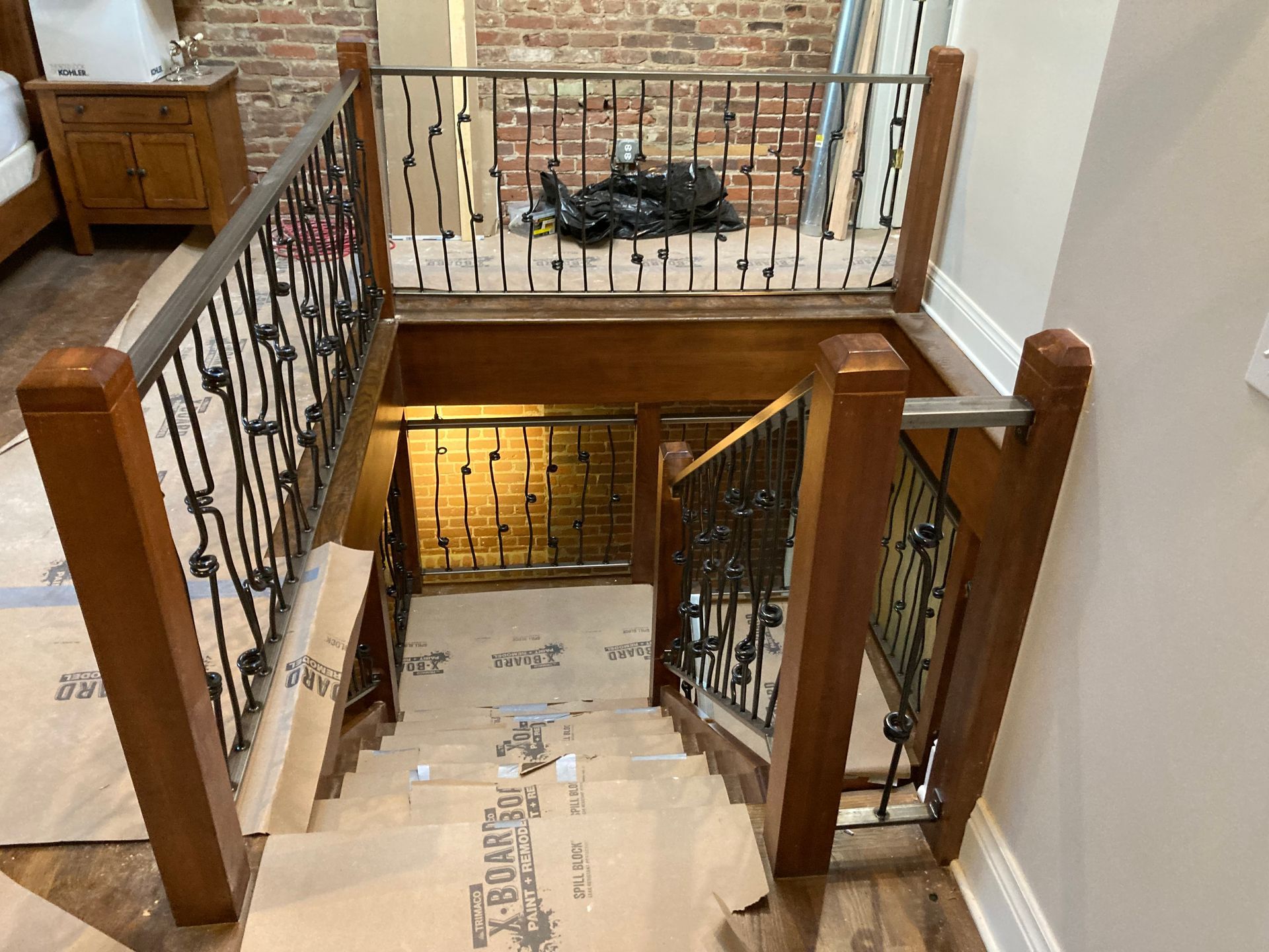 Staircase with ornate black iron railings, wooden posts, and a landing.