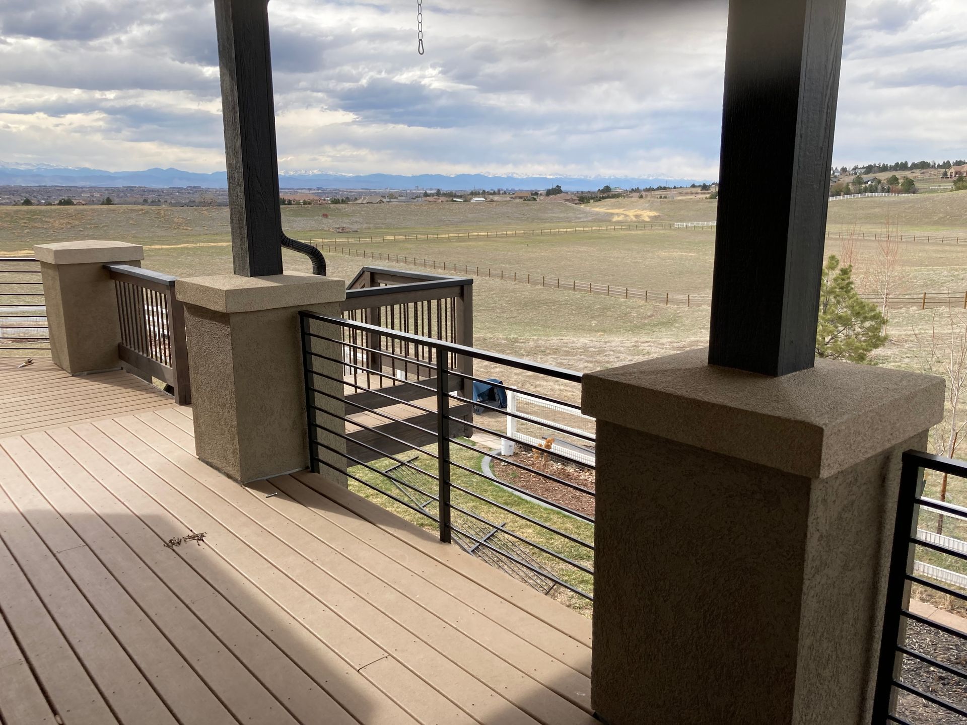 Deck with cable railings, columns, and a vast outdoor view of fields and mountains.