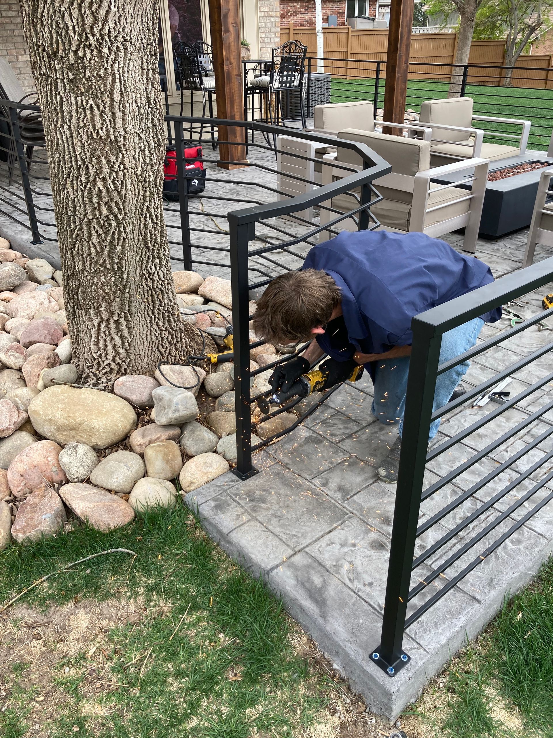 Person installing a black metal handrail on a patio.