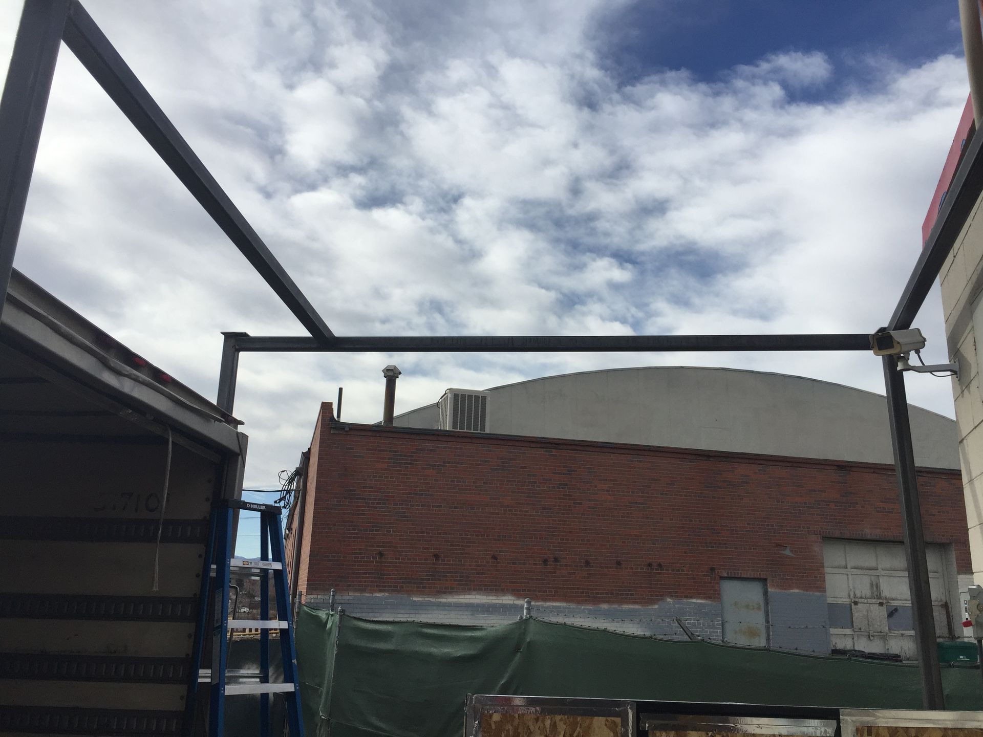 Metal frame structure over buildings against a cloudy sky.
