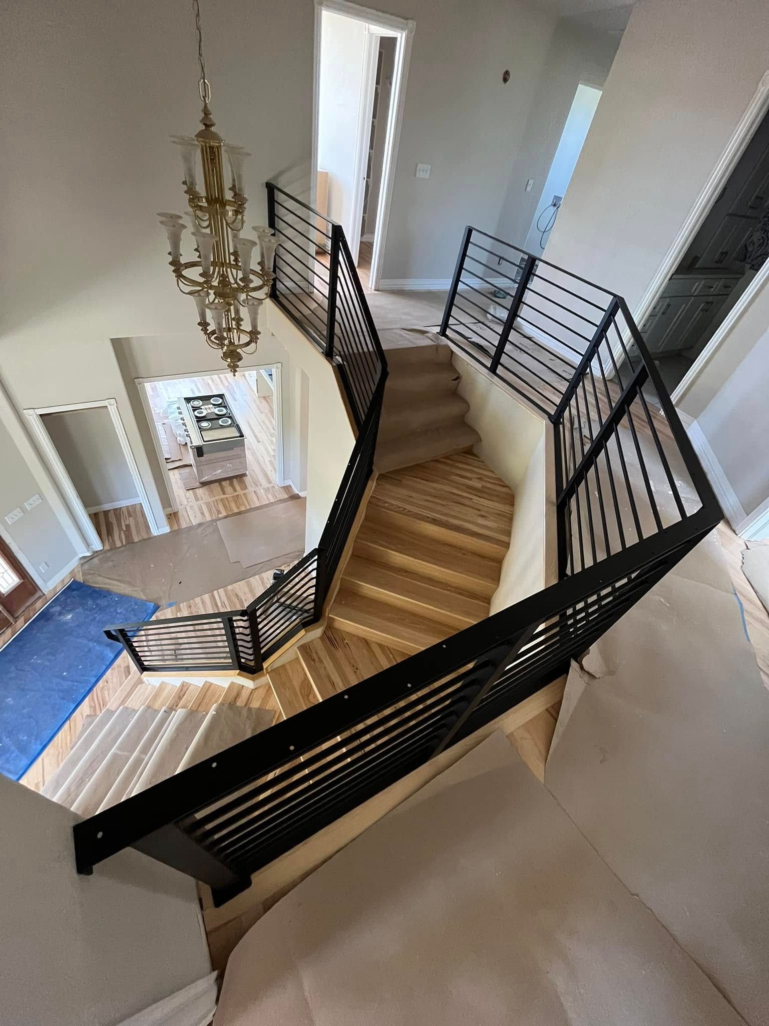 A winding staircase with black metal railings and light wood steps in a house.