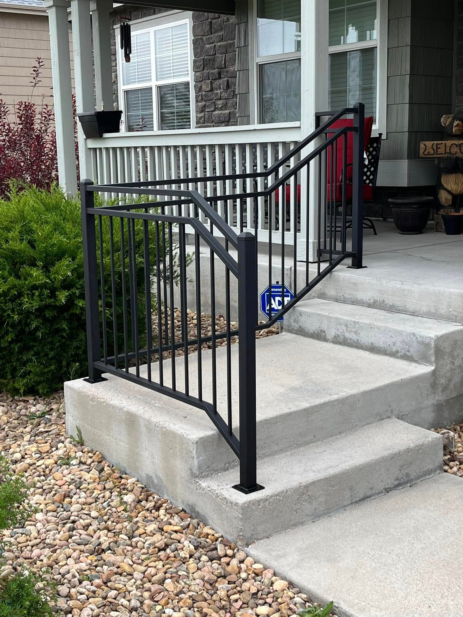 Black metal handrail on concrete steps leading to a front porch.