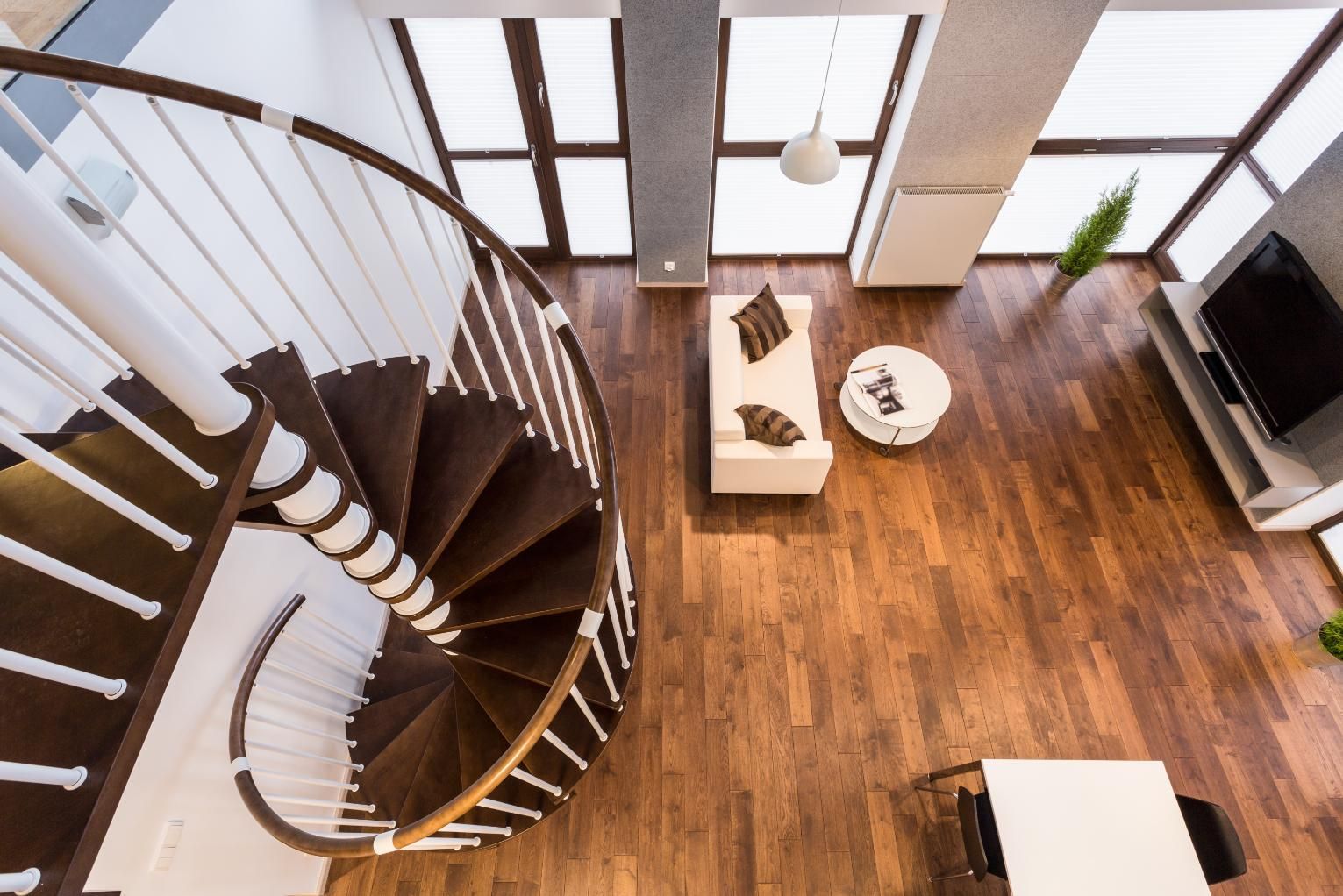 High-angle view of a modern living room with a spiral staircase, hardwood floors, and a couch.