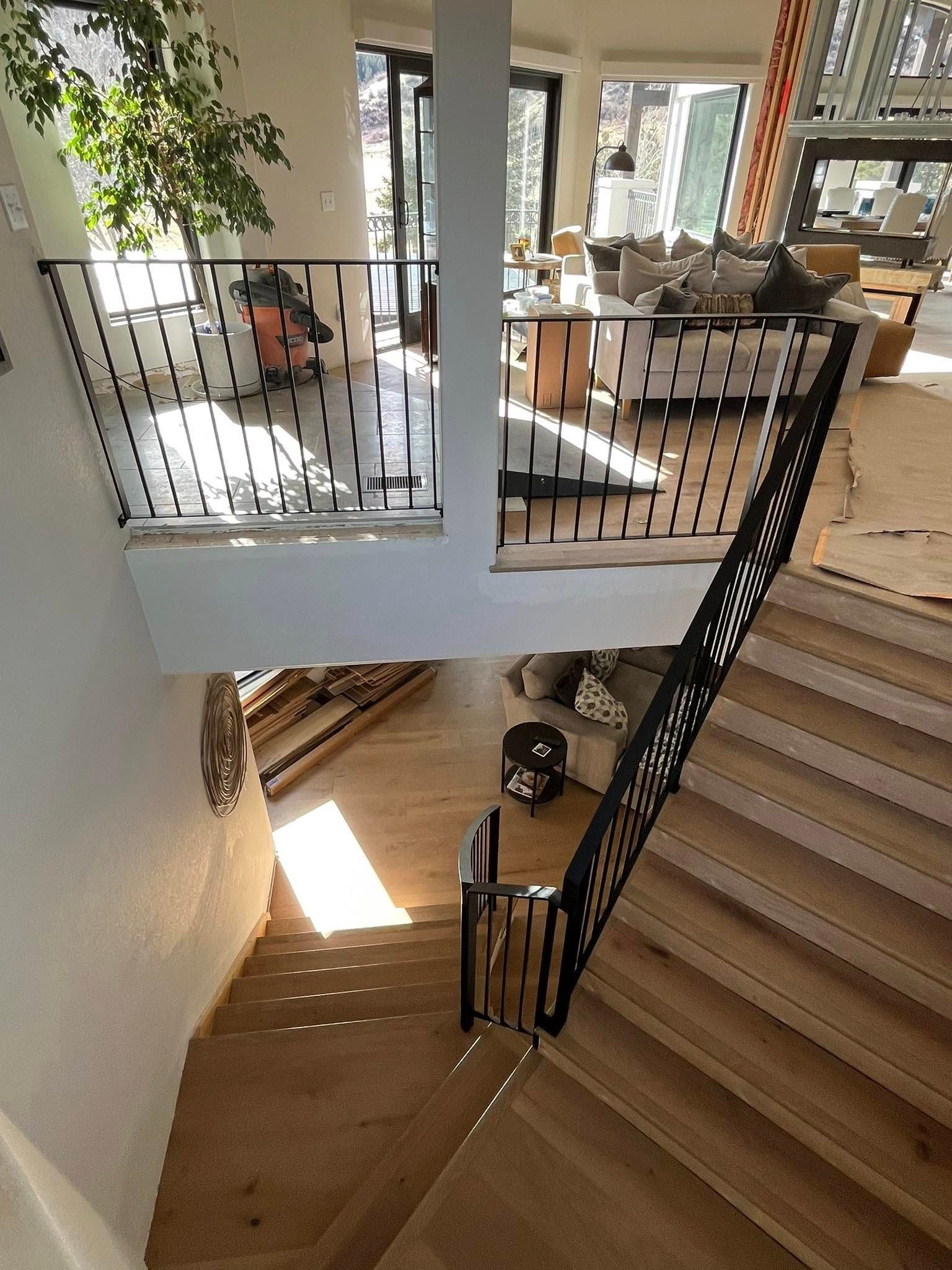 A staircase with black metal railings and wooden steps in a light-filled home.