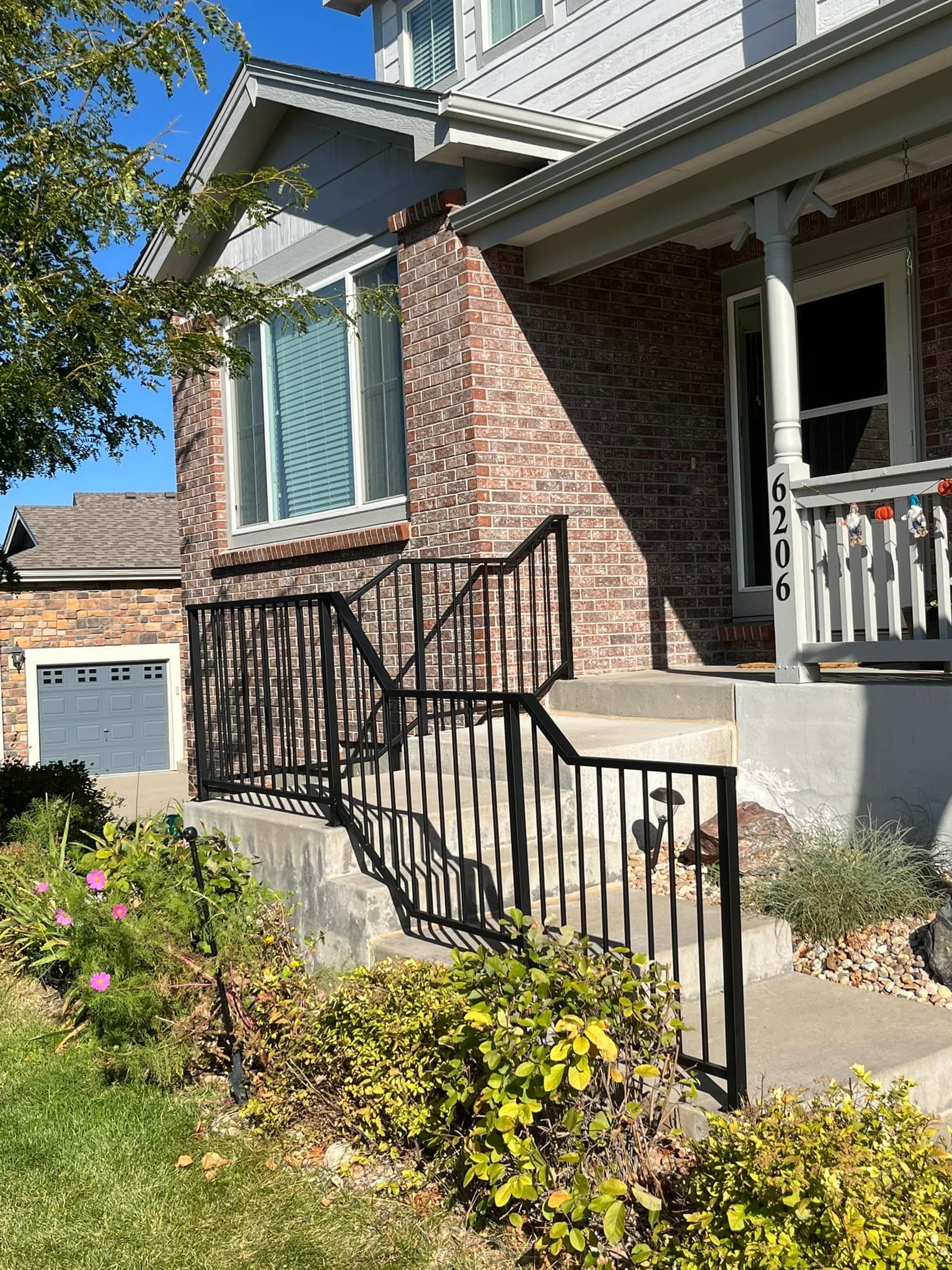 A two-story house with a brick facade and a black iron railing leading to the entrance.