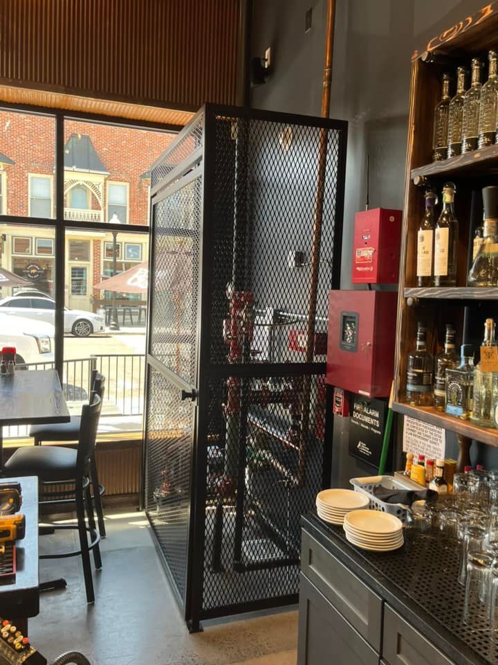 Bar interior with a metal cage wine rack, countertop, and window with street view.