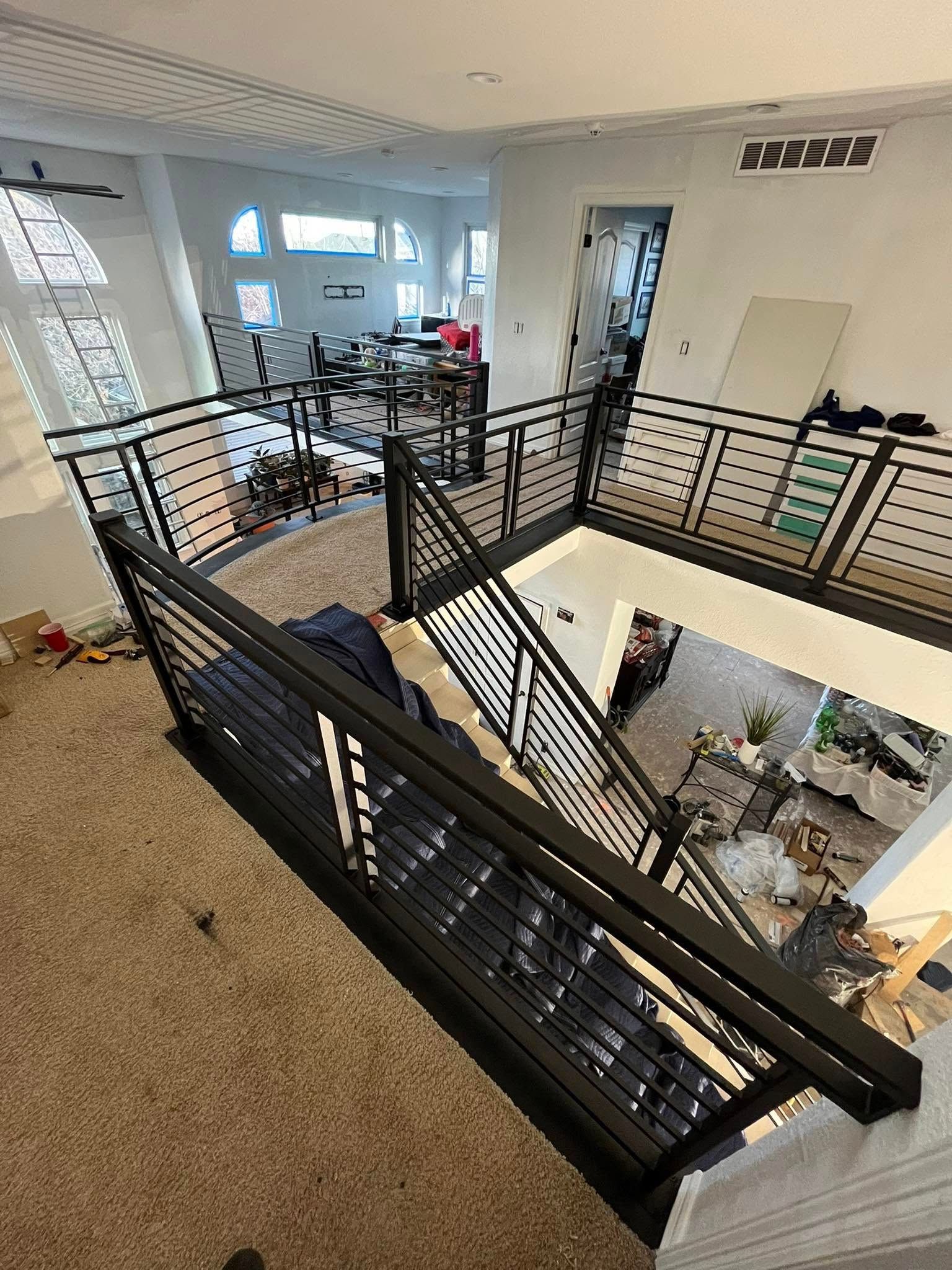 Interior view of a home with a staircase and black metal railing overlooking a lower level.