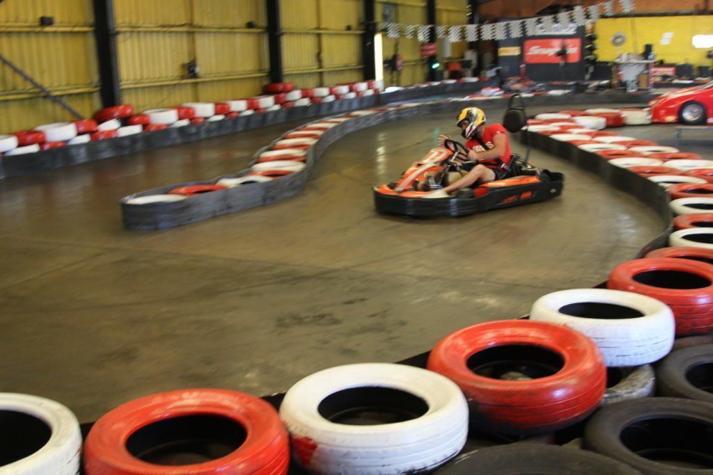 A person is riding a go kart on a track surrounded by tires