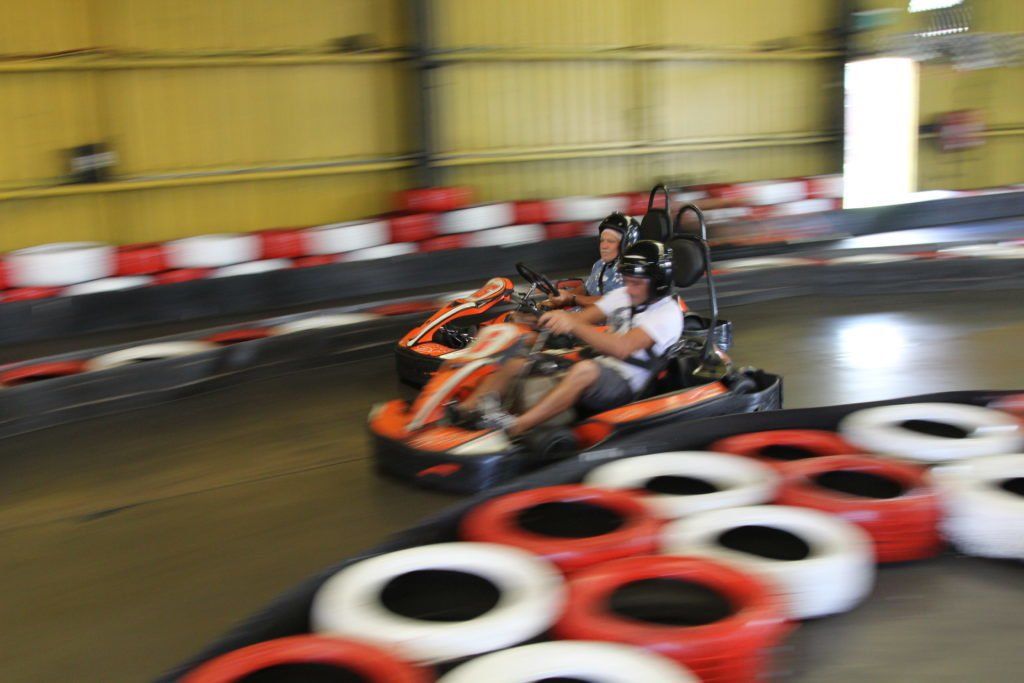 Two people are riding a go kart on a track