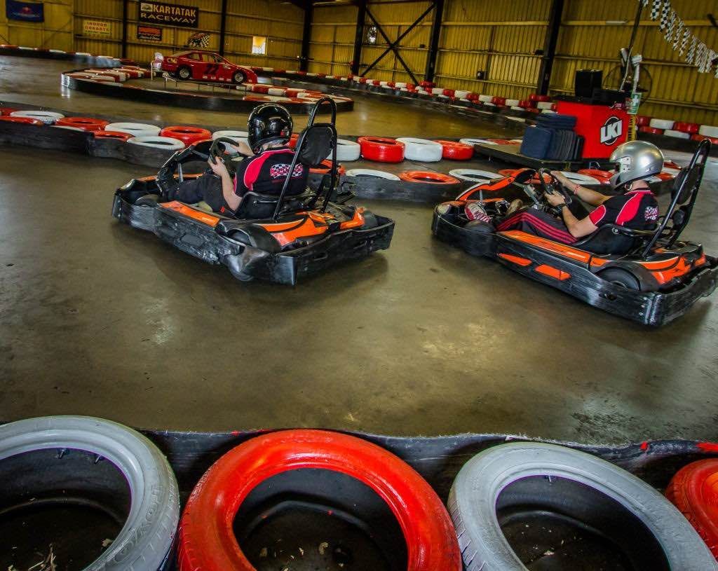 Two people are riding go karts on a track.