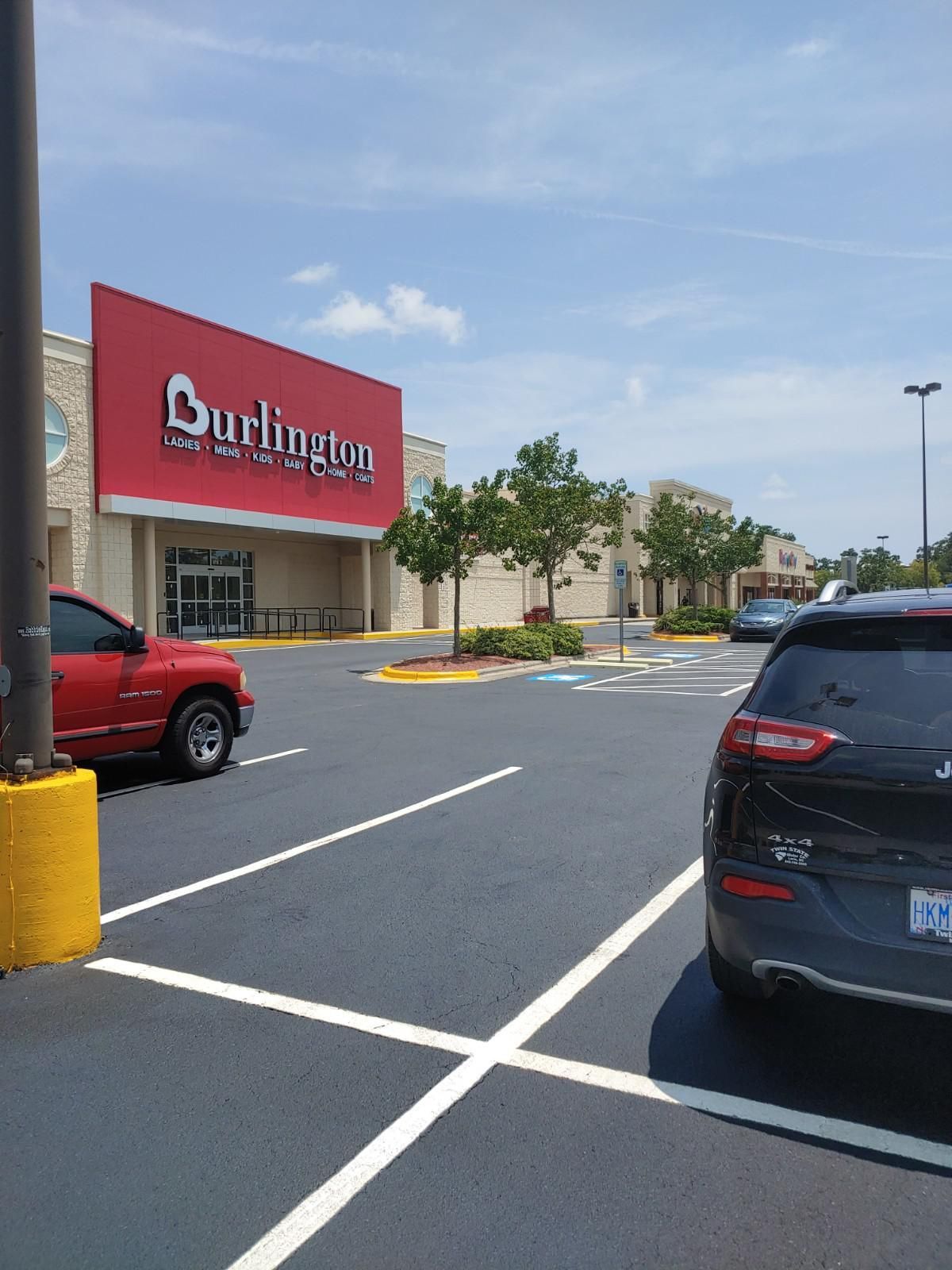 Burlington store exterior with red sign, parked cars, and blue sky.
