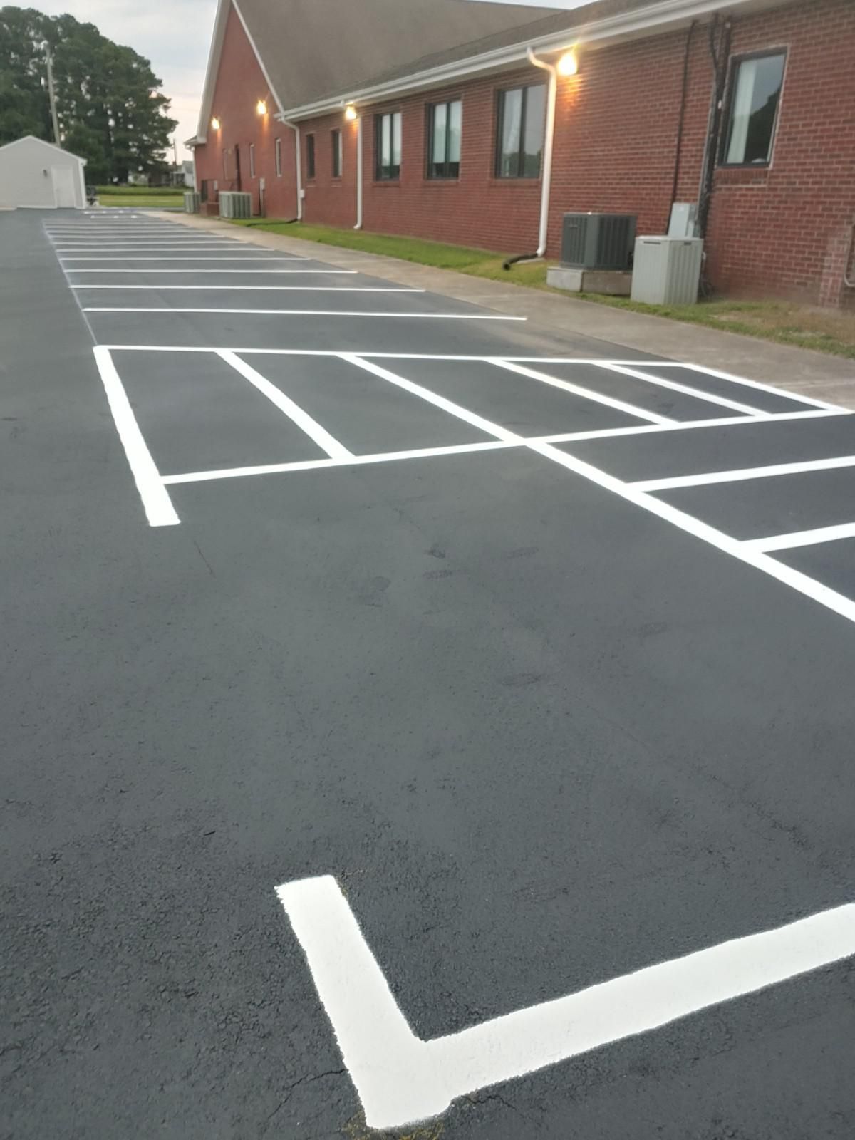 Parking lot with white painted parking space lines next to a brick building.
