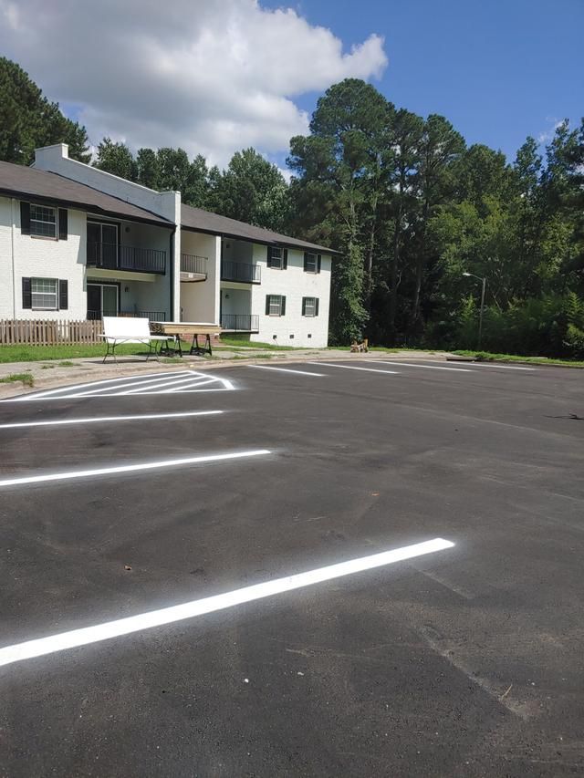 Apartment building with freshly painted parking spaces. Clear blue sky, trees in the background.