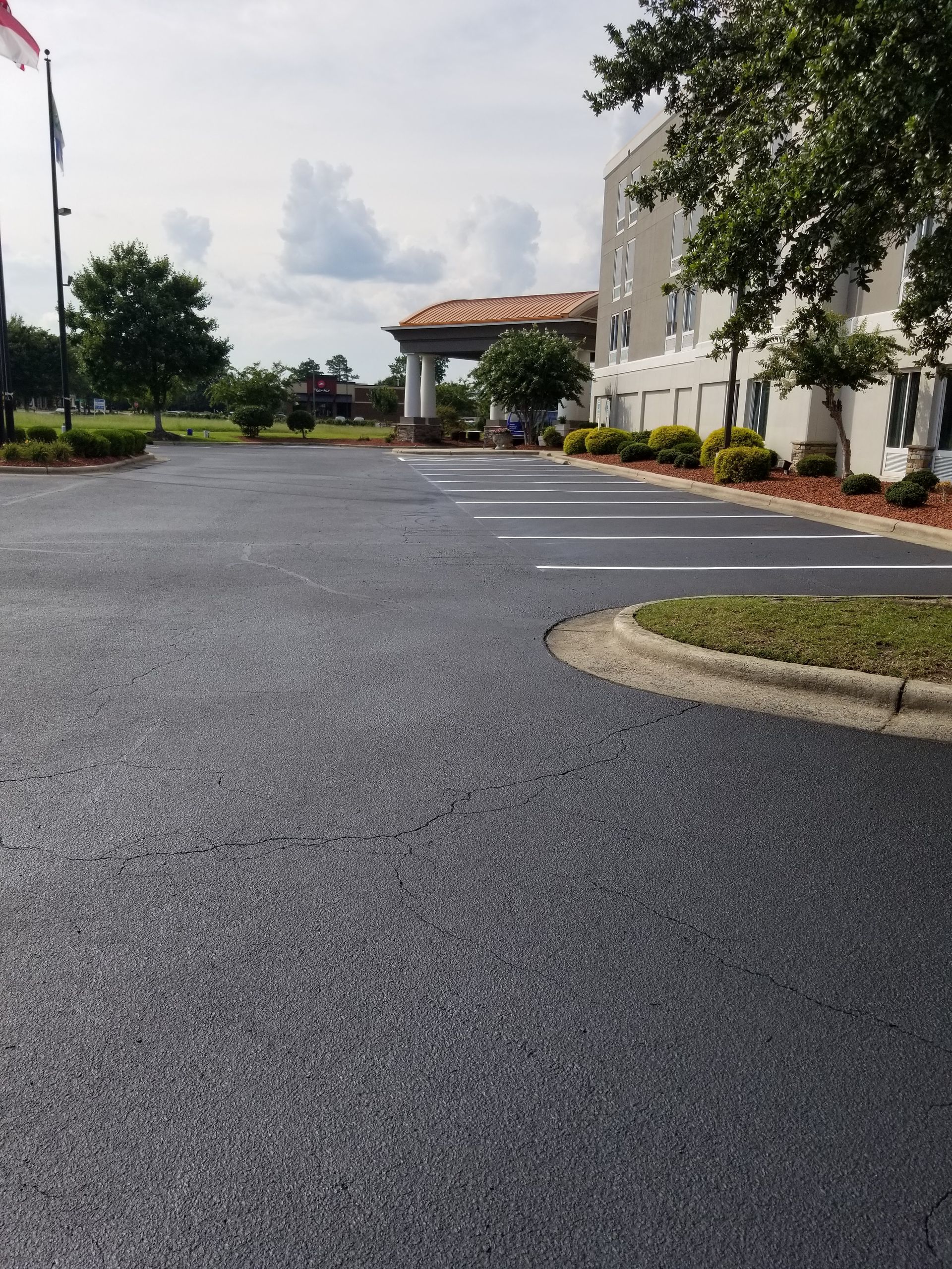 Newly paved asphalt parking lot at a hotel, with painted white parking space lines.