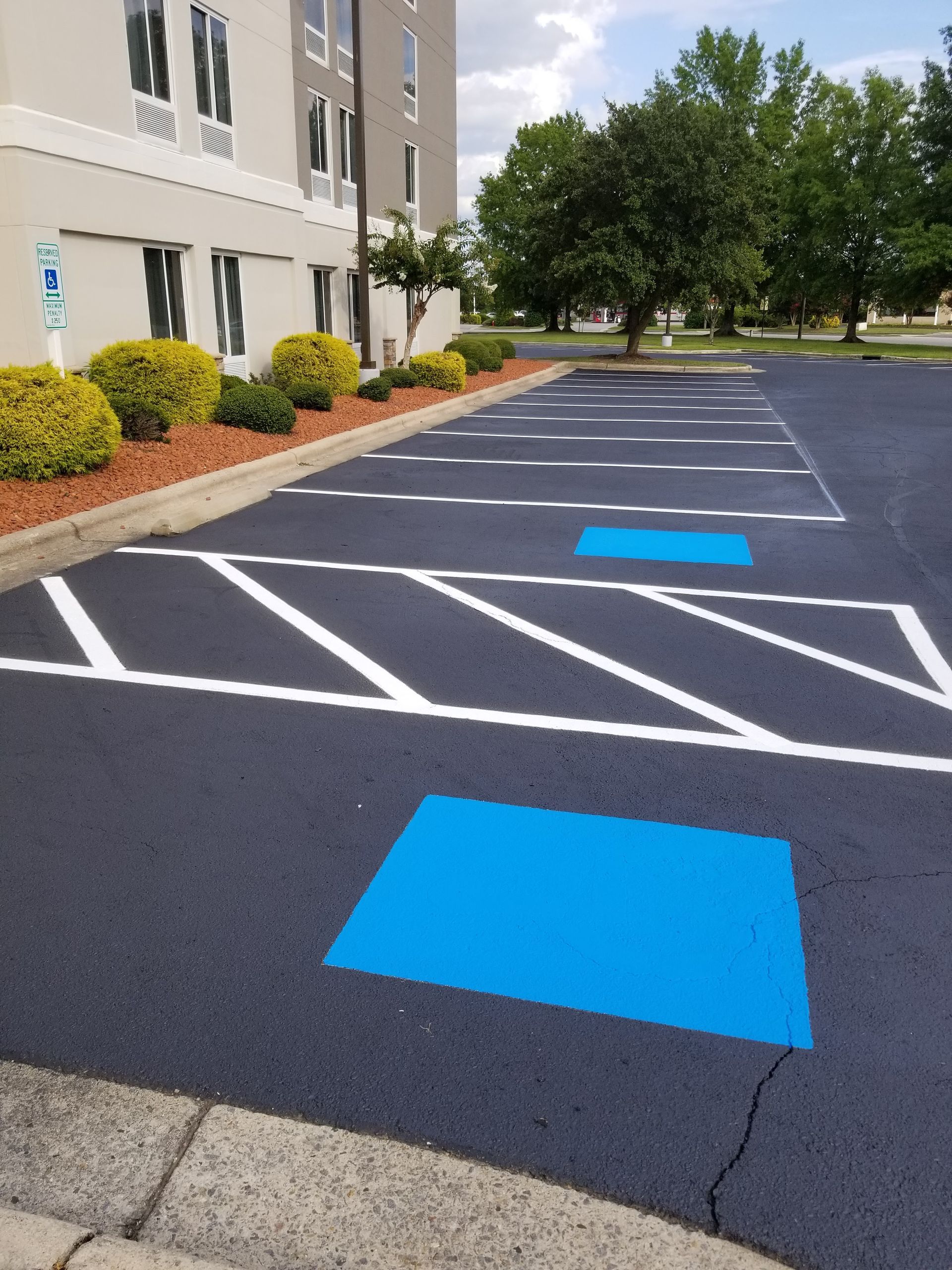 Parking lot with fresh white lines and two blue accessible parking spaces. Building in background.