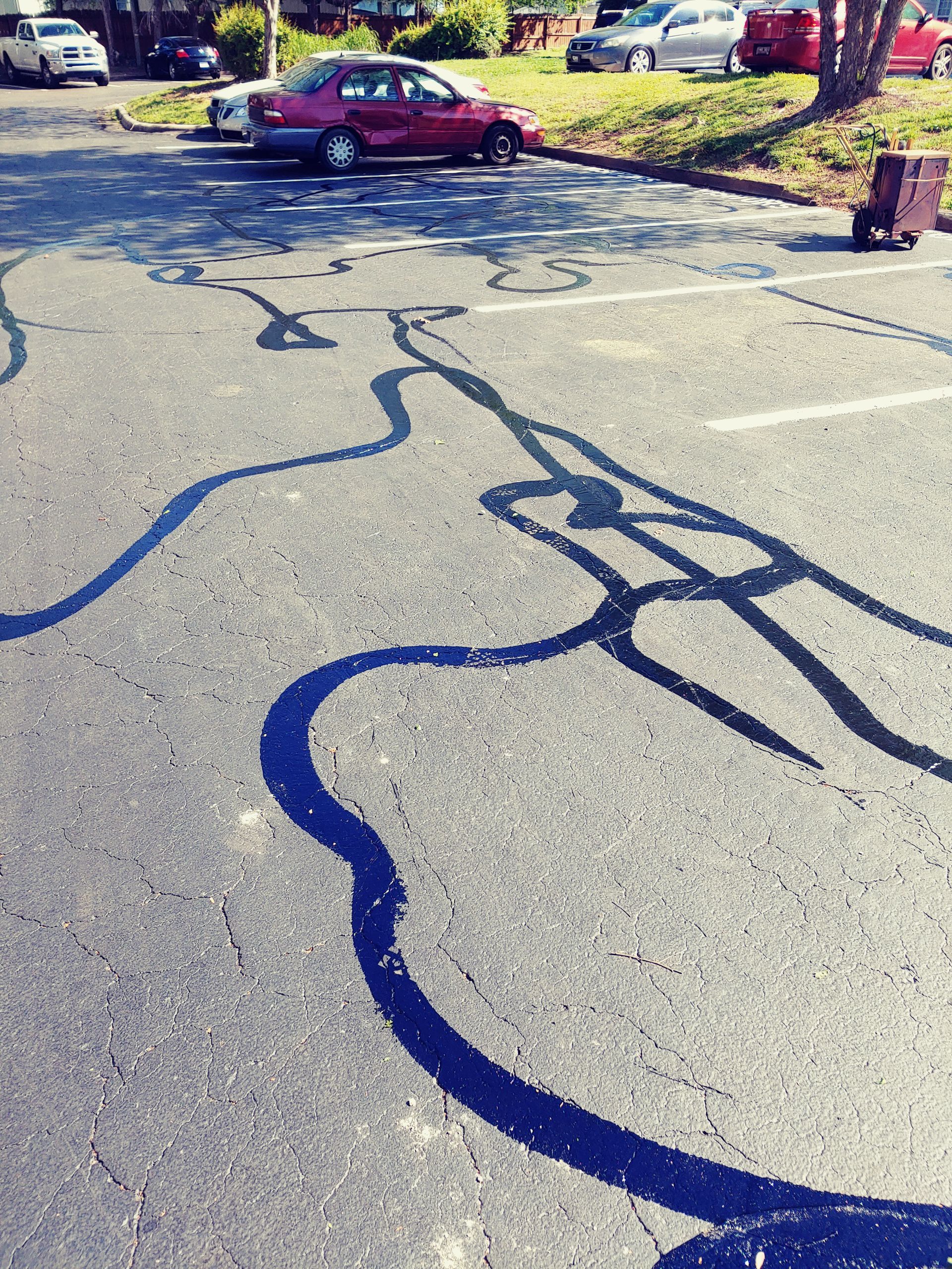 Blue lines painted on asphalt, resembling a stylized human figure, in a parking lot.