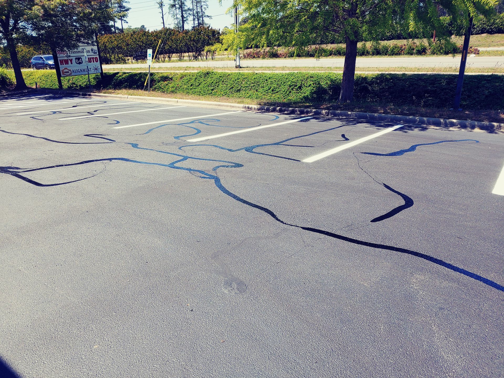 Parking lot with tire marks, trees, and grass.
