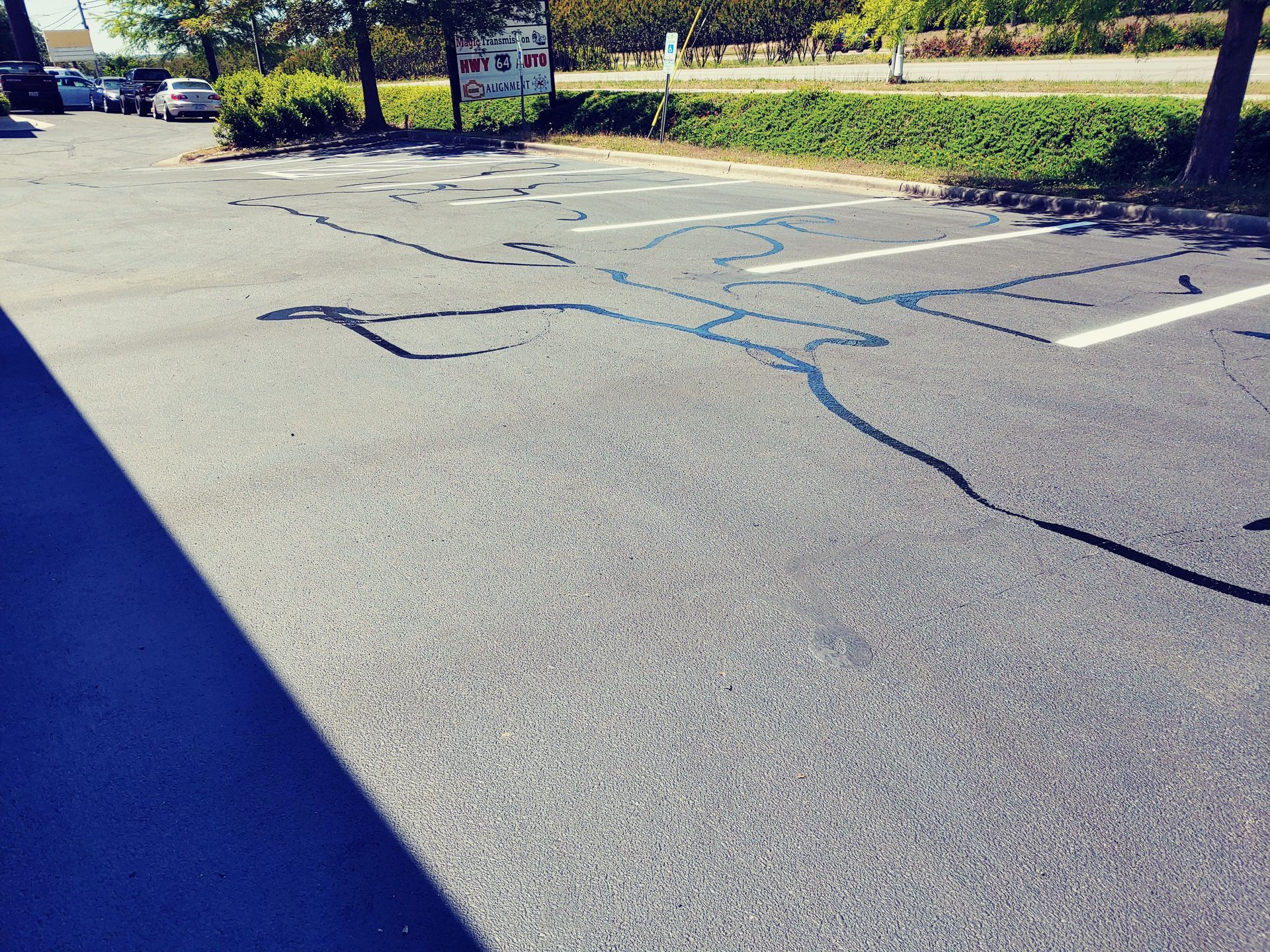 Blue outline on asphalt, resembling a person, stretches across parking spaces.