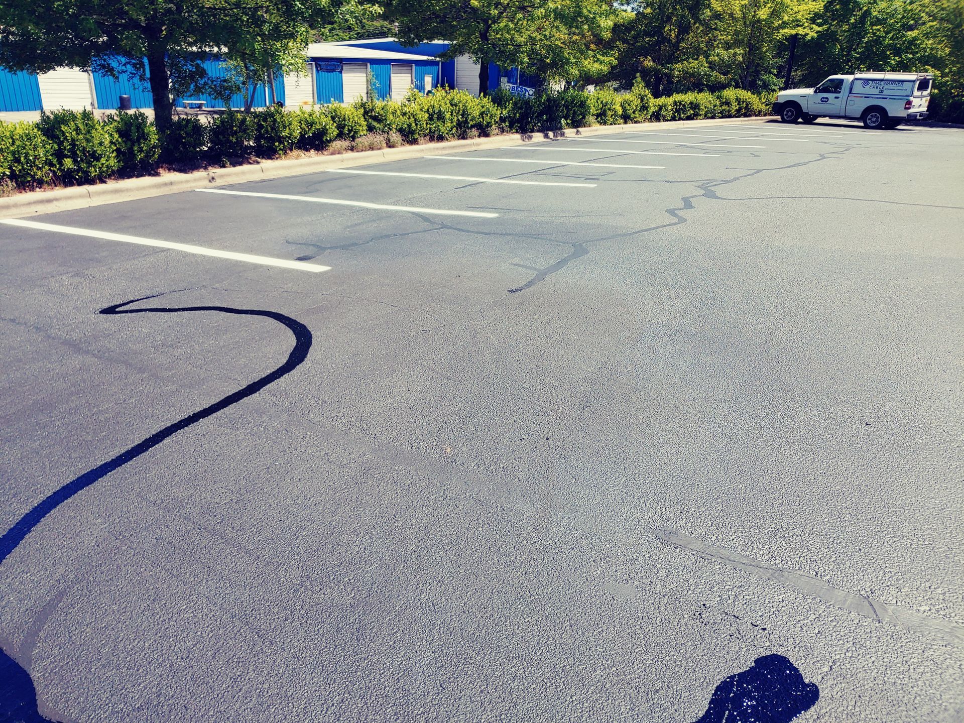 Empty parking lot with white lines. A white truck and building are in the background.